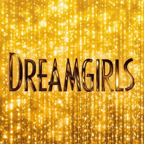 Gold glittery background with the word 'Dreamgirls' in black text.