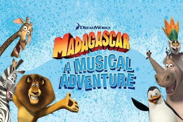 Promotional poster for "Madagascar: A Musical Adventure" featuring animated characters from the DreamWorks movie, including Marty the zebra, Alex the lion, Gloria the hippo, Melman the giraffe, King Julien the lemur, and Mort the lemur, against a blu
