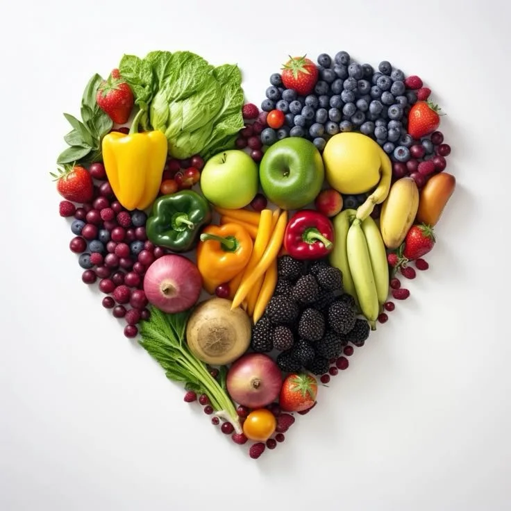 Varietà di frutta e verdura disposta a forma di cuore su sfondo bianco.