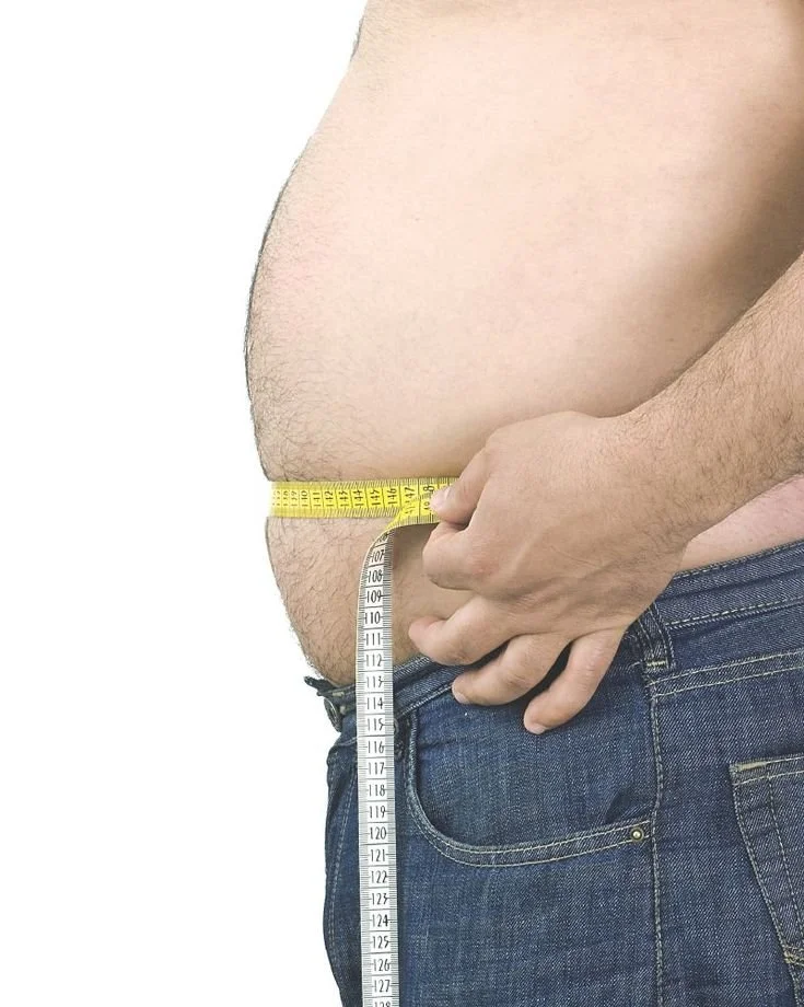 Persona in jeans misura la circonferenza della vita con un metro a nastro.