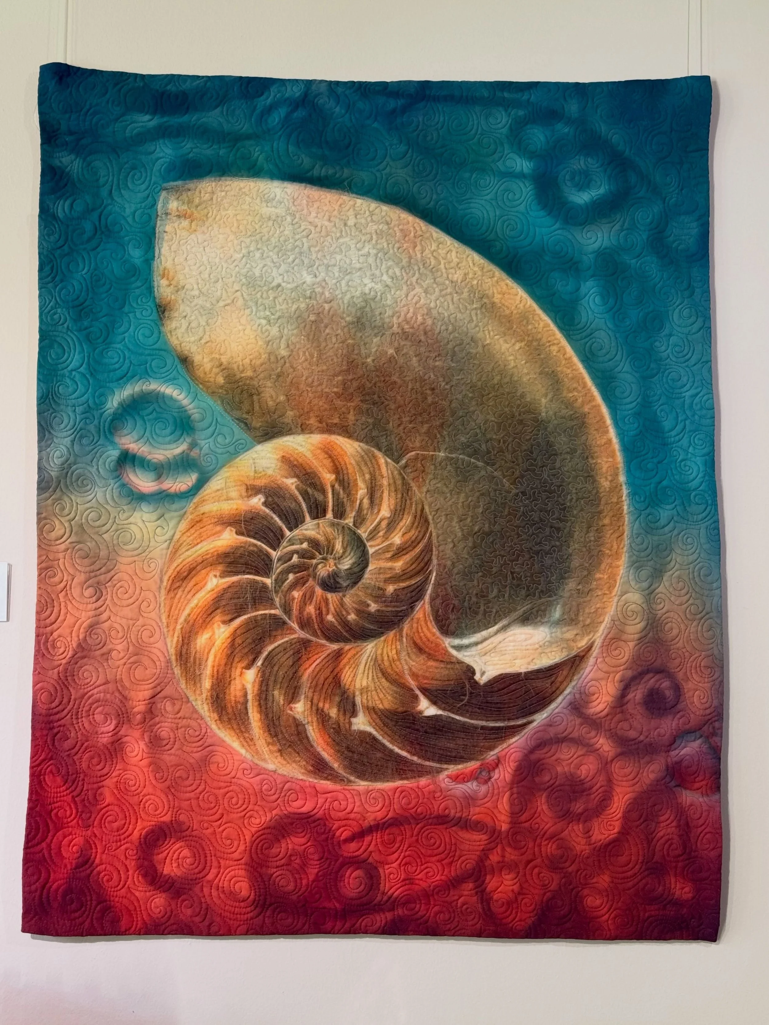 From a distance, the shell pulls you in through color and scale. Up close, the stitching becomes part of the image &mdash; following the curves, textures, and natural spiral of the form.

That shift between the whole piece and the details is part of 