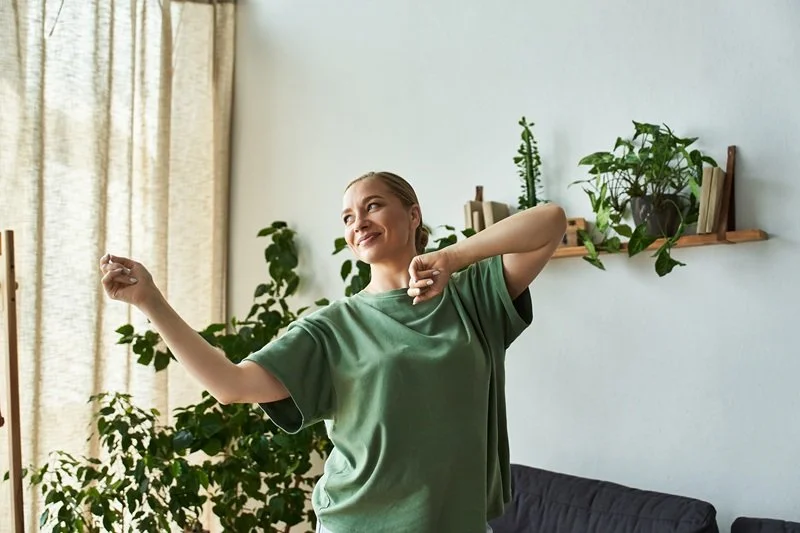 A woman moving through a grounded dance sequence at home. Calm expression. No mirrors. No gym equipment.