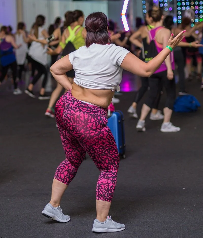 group dance class with focus on plus size woman facing away from camera