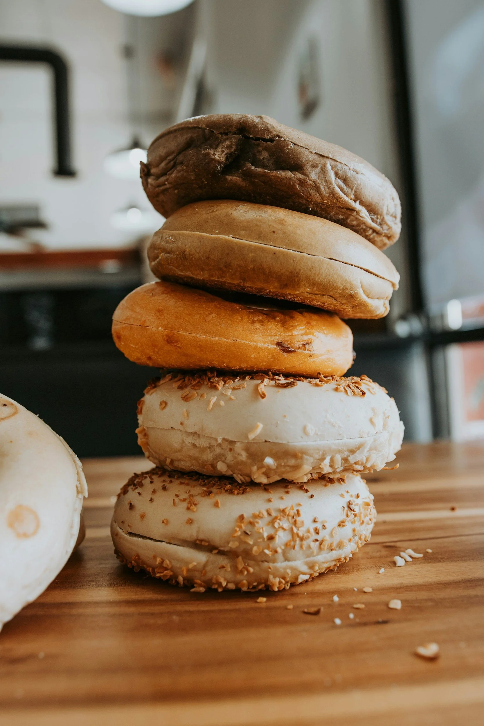 A stack of five assorted cookies on a wooden surface in a cozy cafe setting.