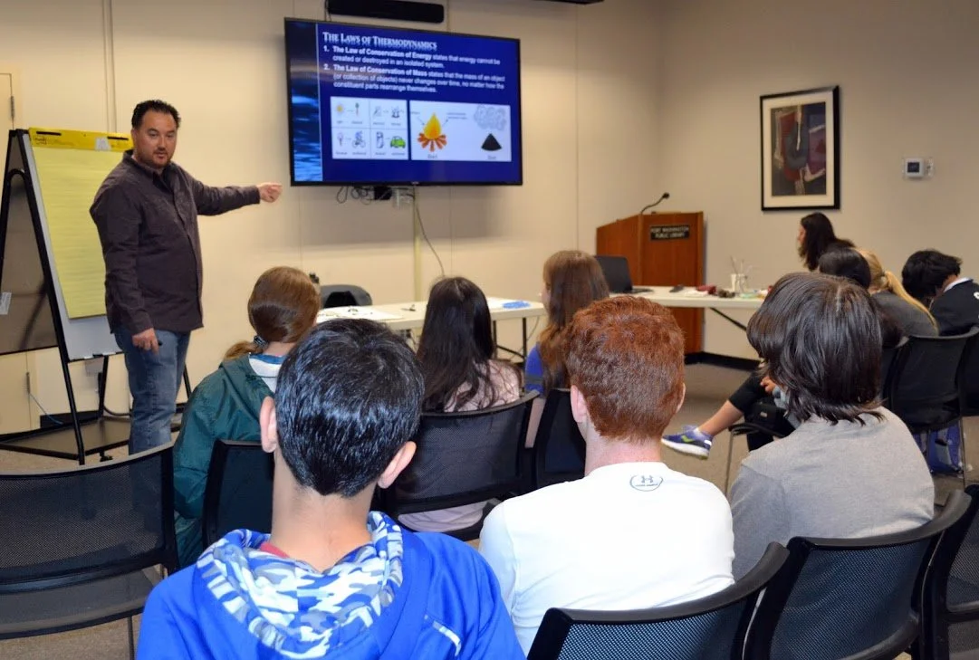 A teacher giving a presentation on thermodynamics to a classroom of students in a conference room.