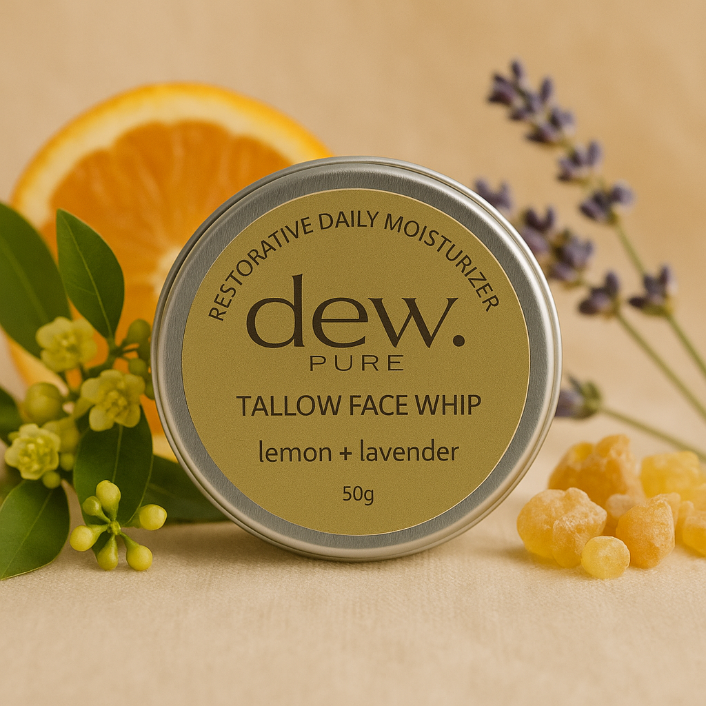 A container of dew. Pure Tallow Face Whip with lemon and lavender, surrounded by an orange slice, lavender sprigs, and yellow wax beads.
