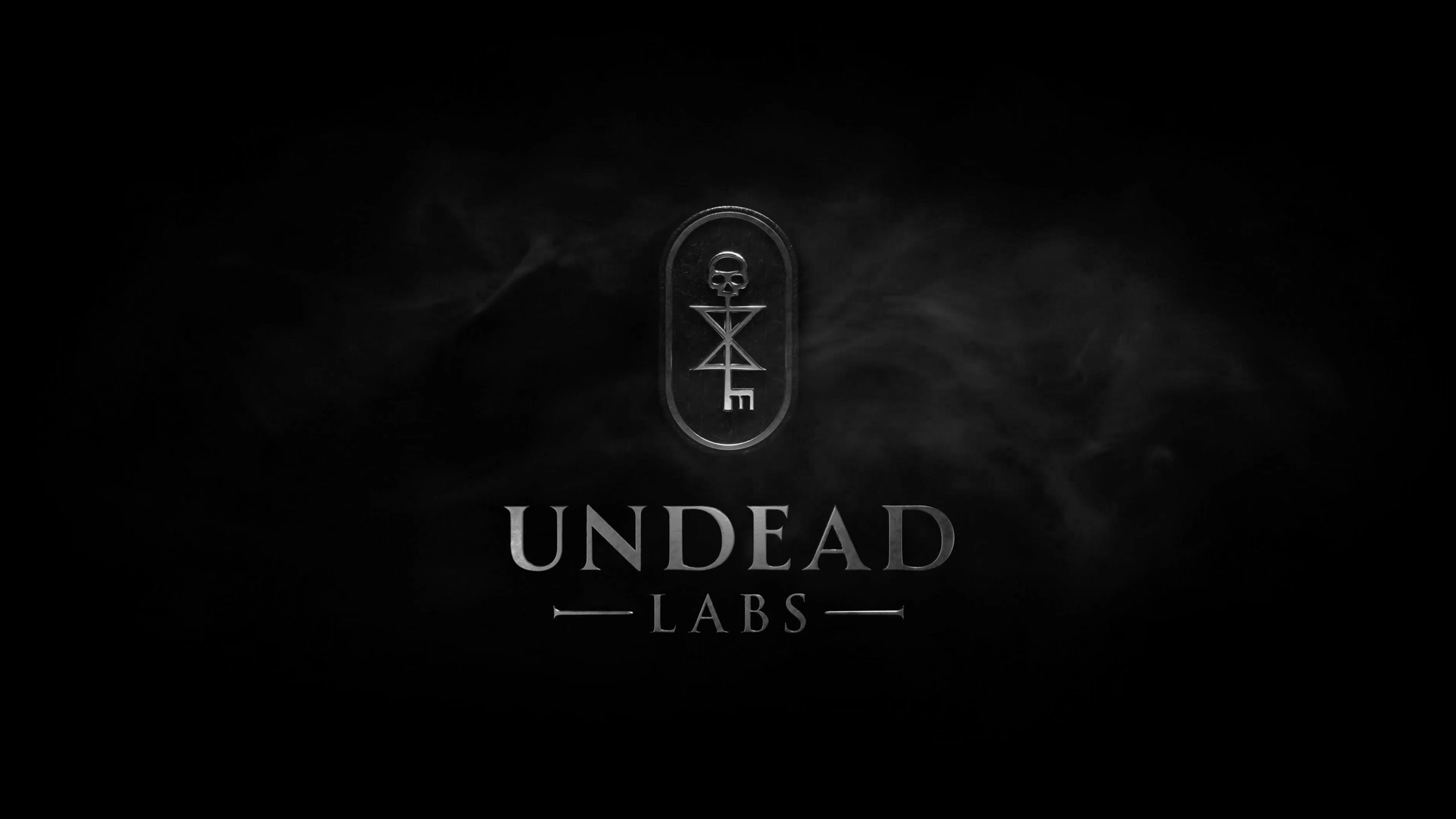 A dark, smoky background features a central emblem with a skull, geometric shapes, and a key, above the text 'Undead Labs'.