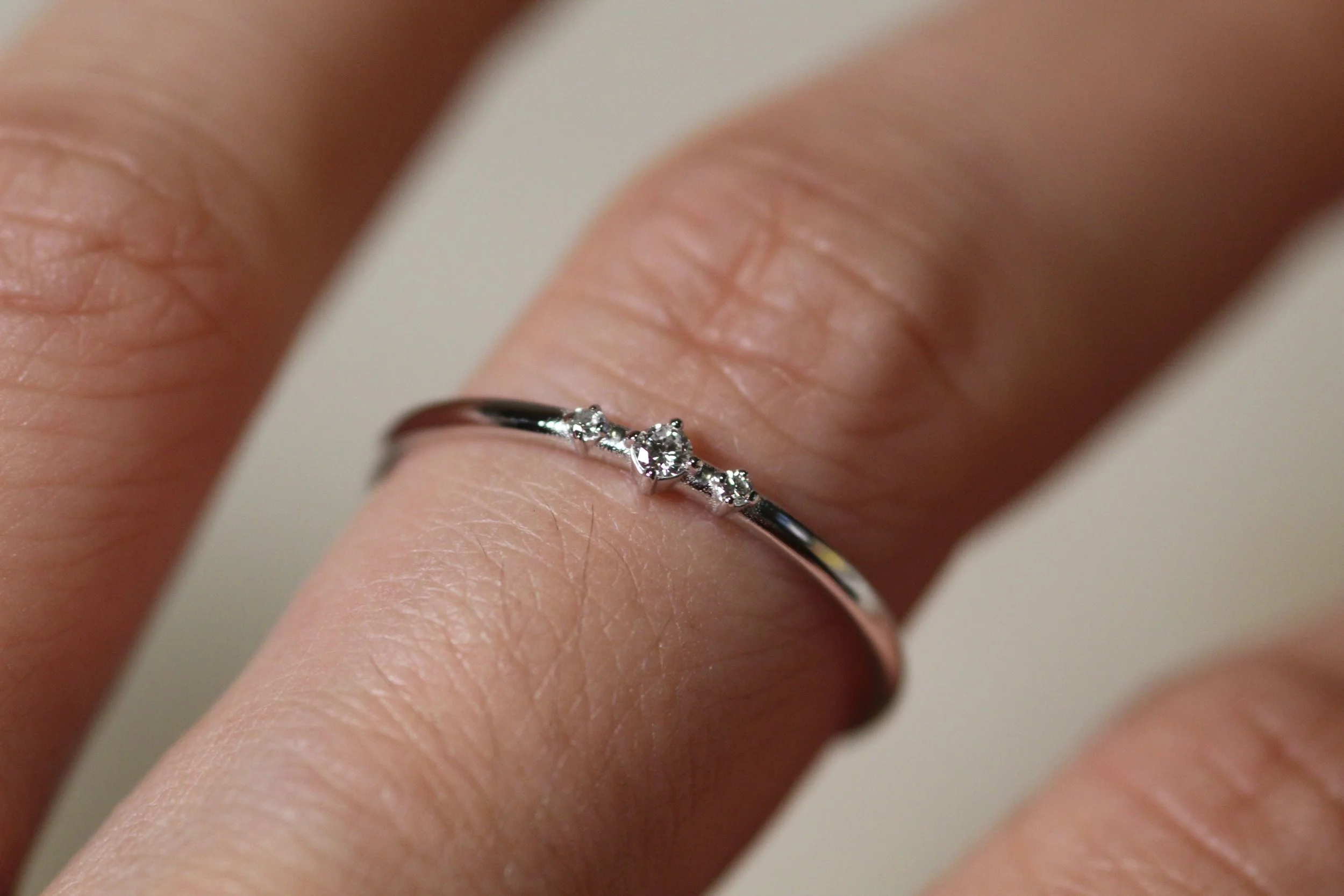 Minimalist trio diamond ring in 14K rose gold, slim band with three sparkling diamonds on finger, elegant stacking ring for everyday wear