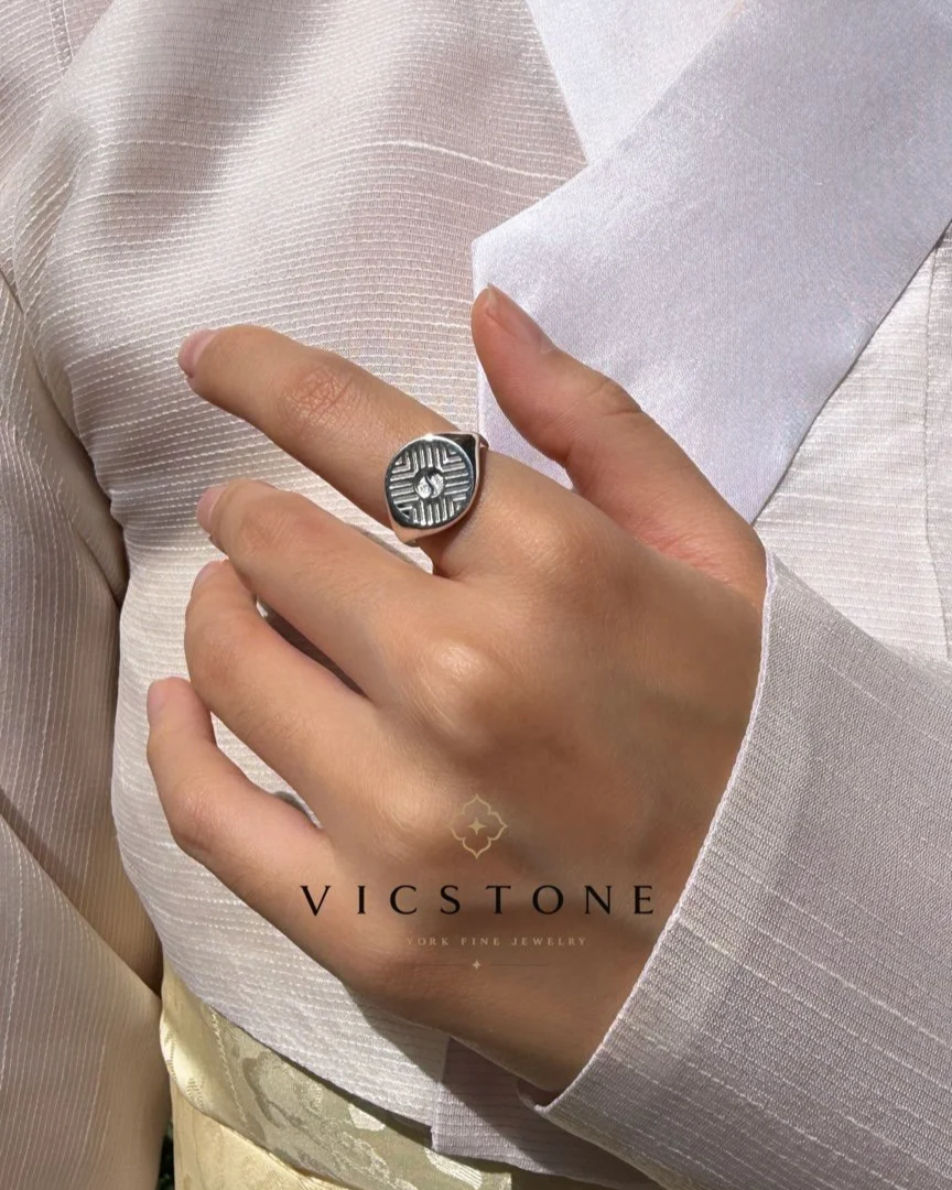 A person wearing a silver ring with a circular, textured design, holding their hand near their chest, with a light-colored, textured fabric in the background. The image features a "VICSTONE" logo and text at the bottom. 태극 반지 yin and yang 광복절 콜라보 한국