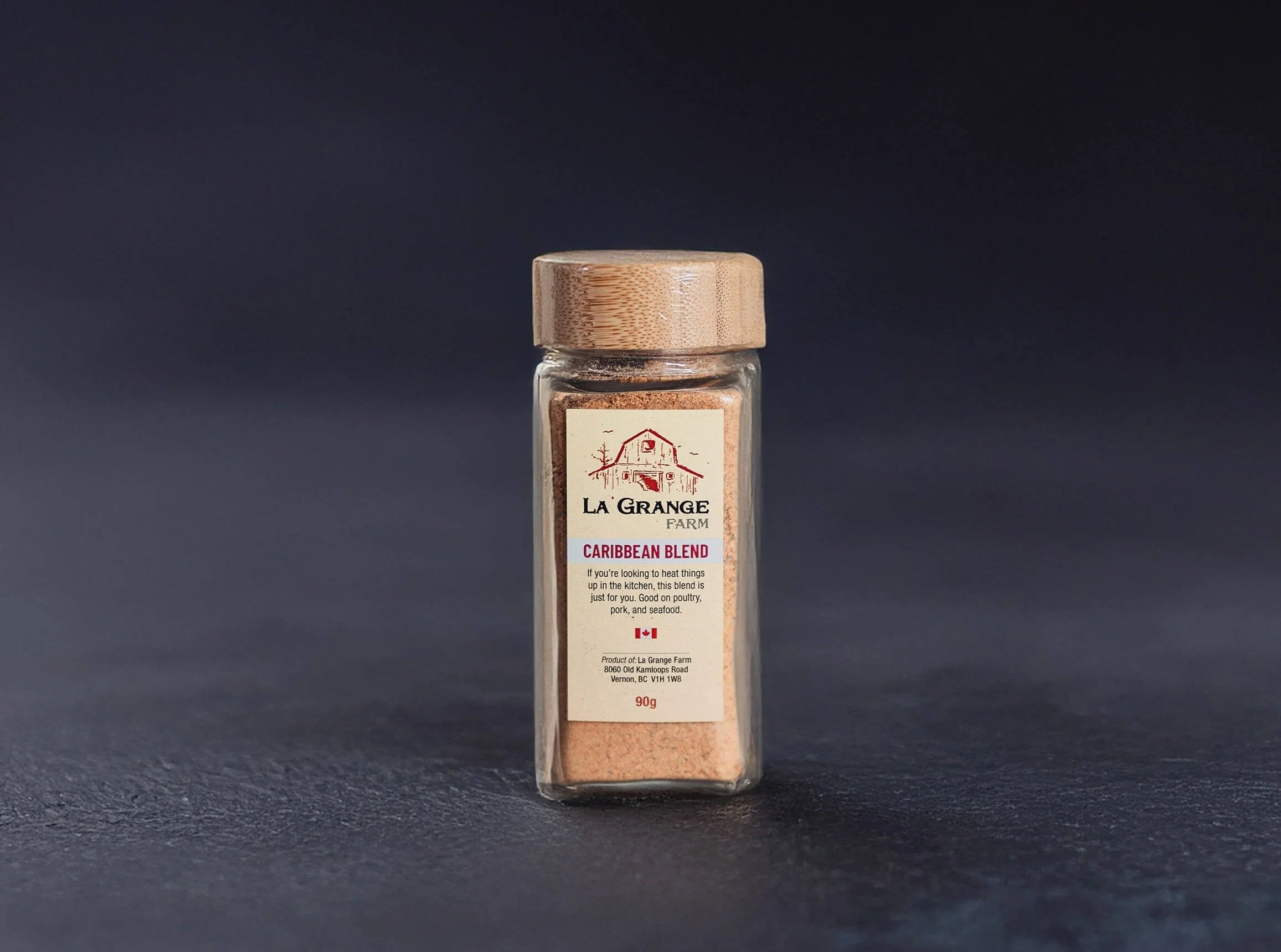 Jar of Caribbean Blend spice from La Grange Farm with wooden lid and beige label on a dark background.