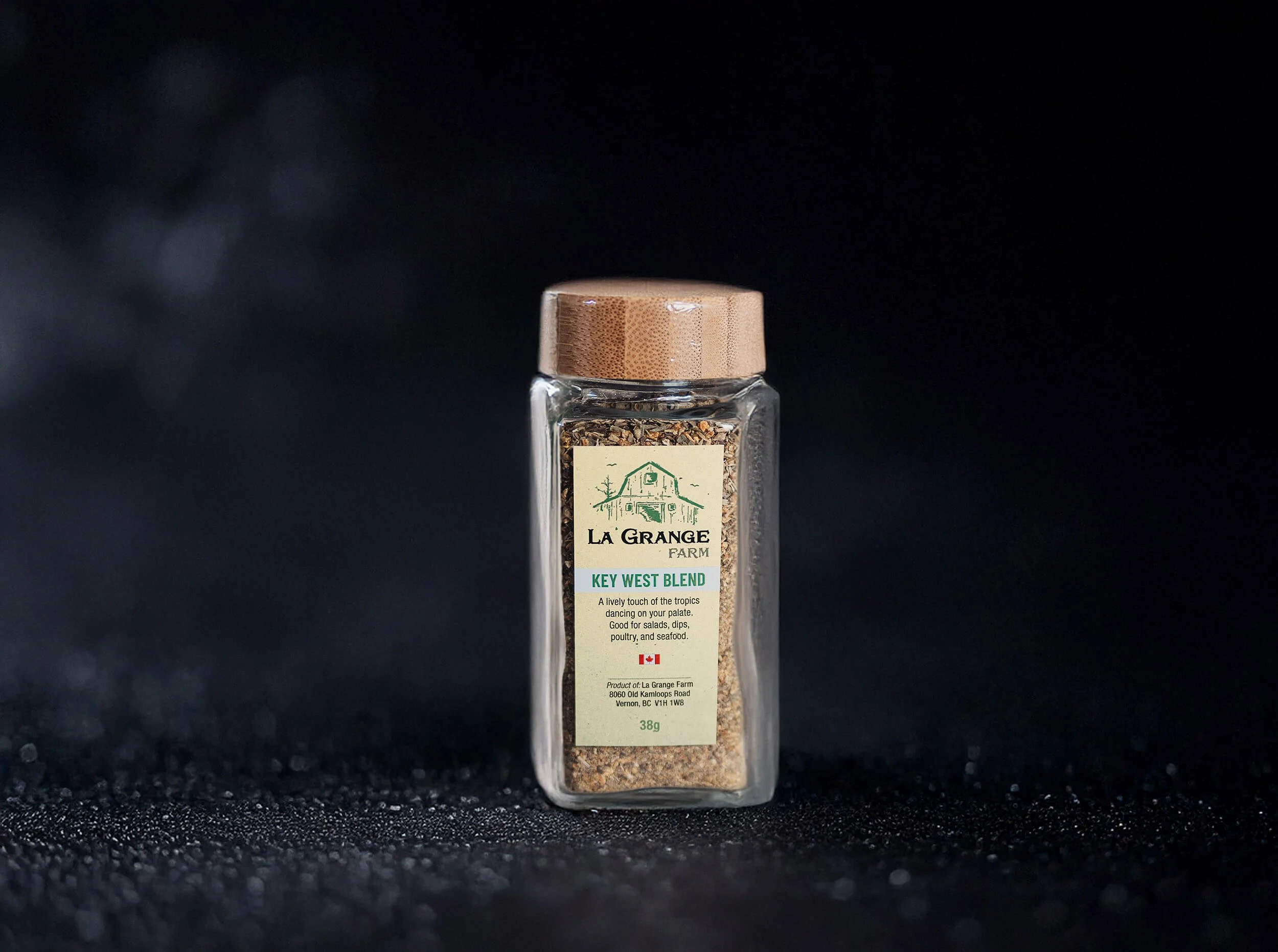 Glass jar of La Grange Farm Key West Blend seasoning with wooden lid.