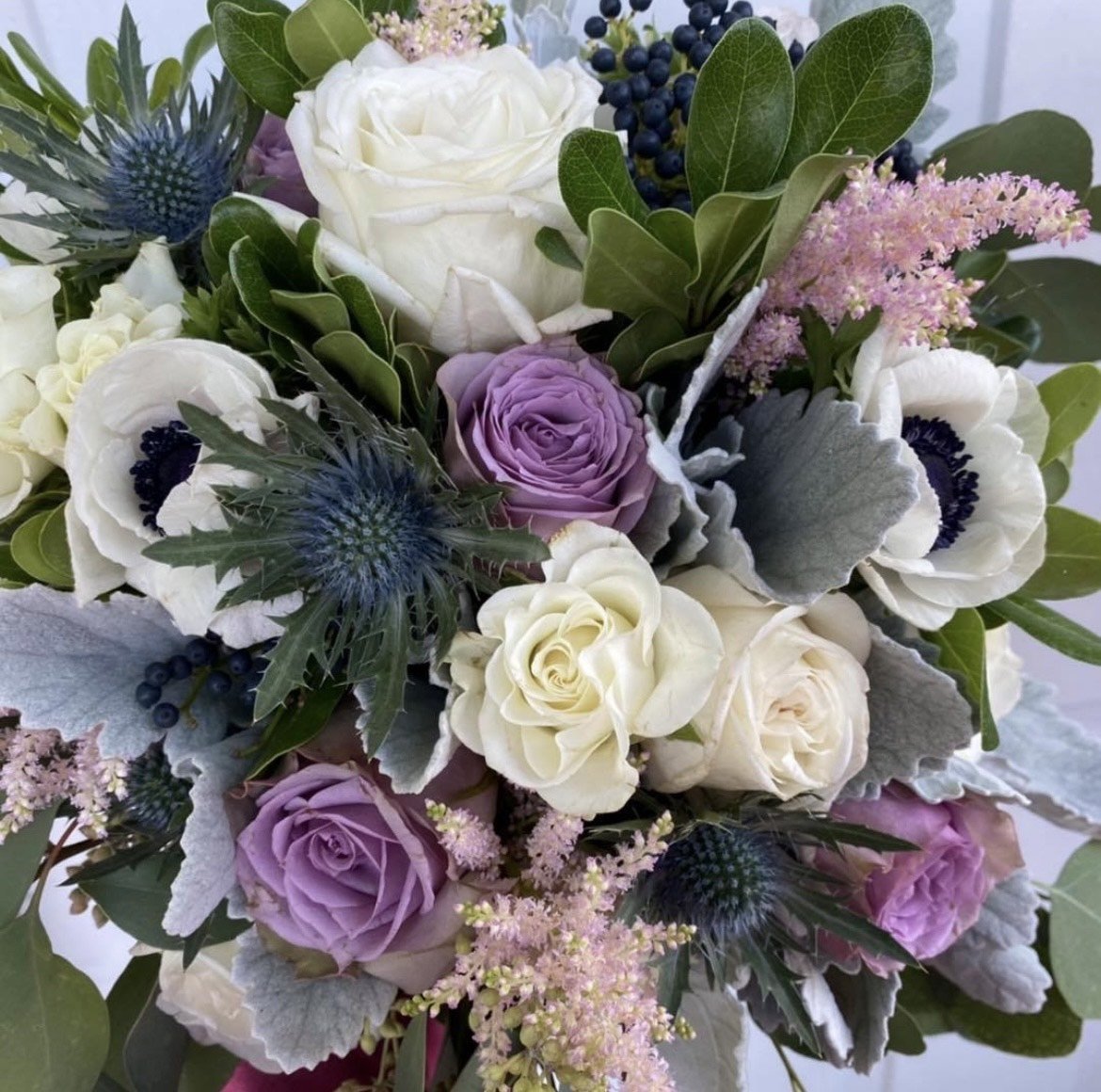 Bouquet with white roses, purple roses, thistles, and greenery