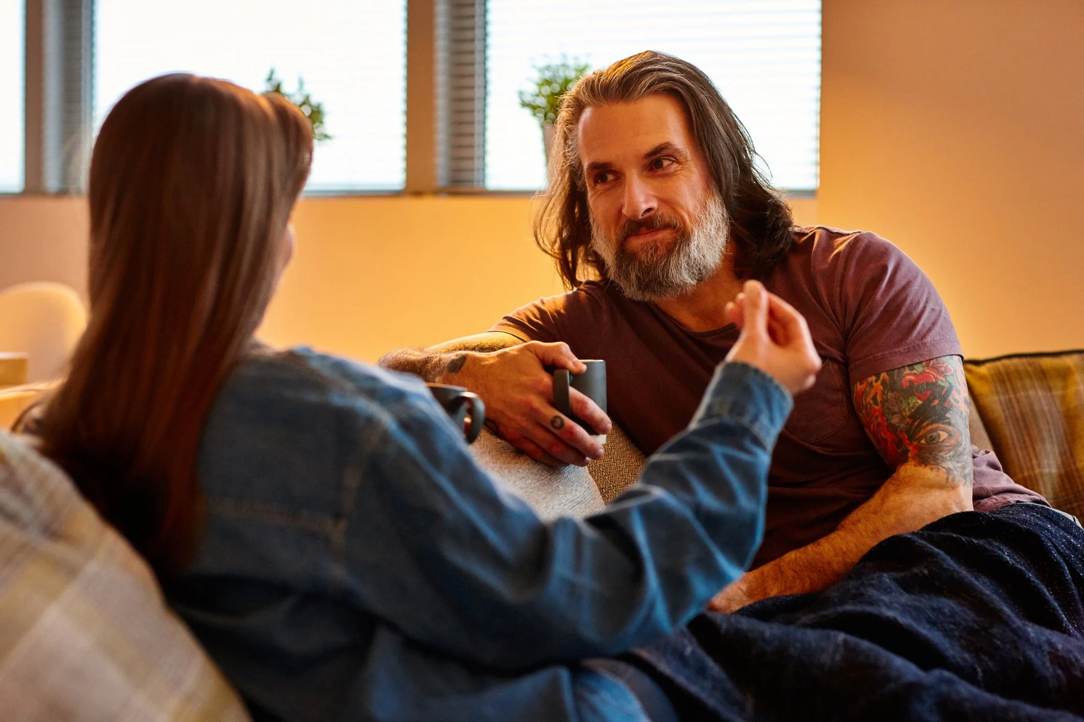 mature couple relaxing on a couch, talking and drinking coffee