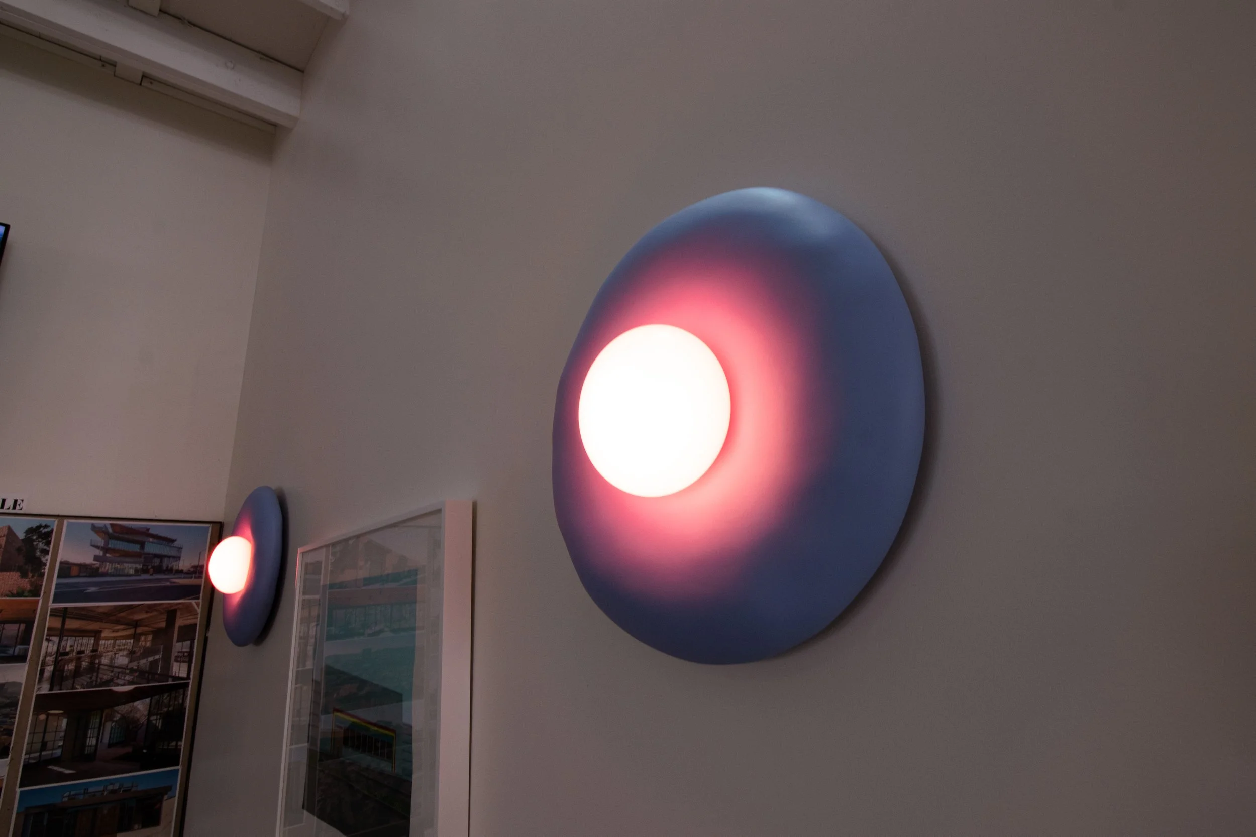 Wall-mounted circular art piece with a glowing white center and blue halo