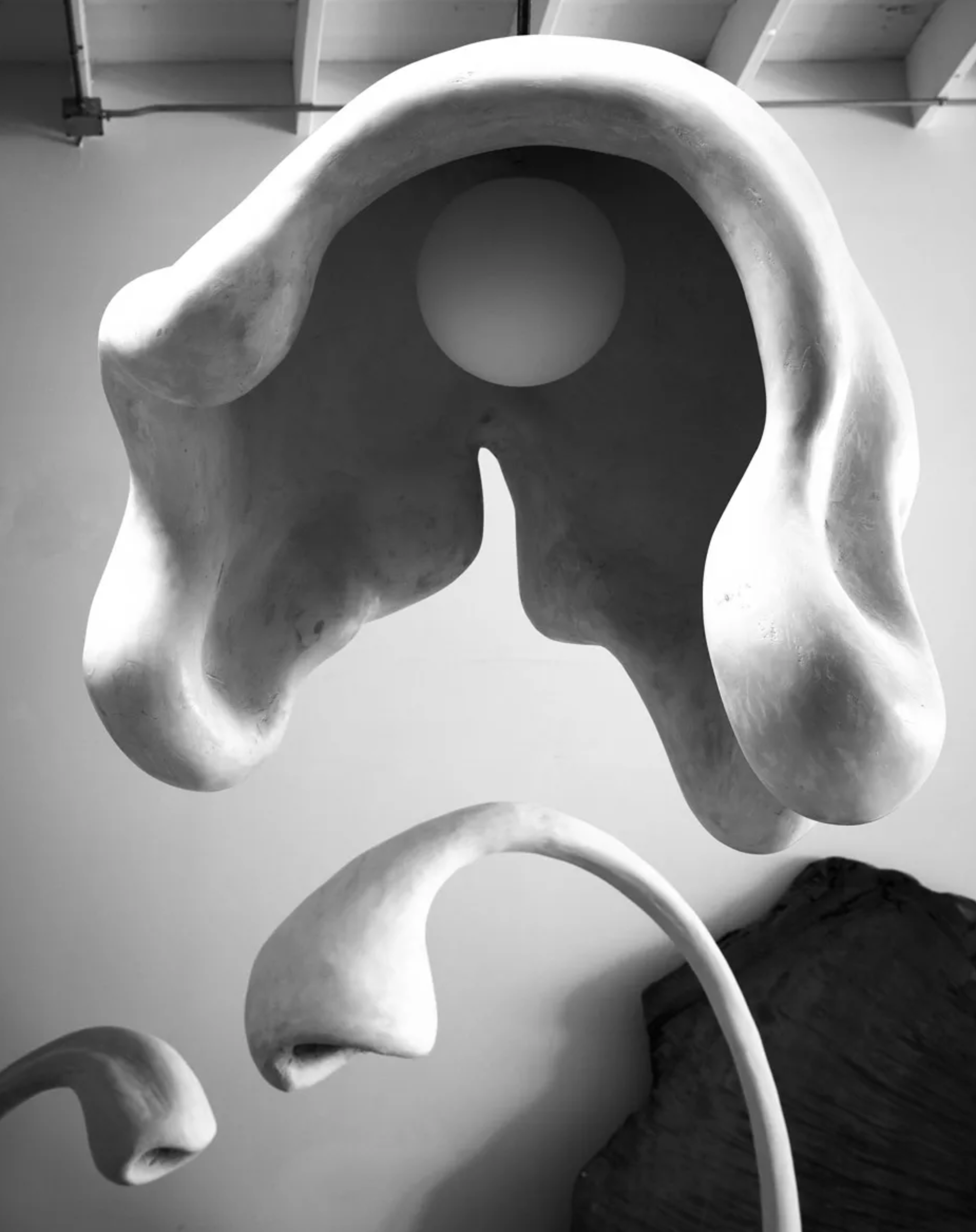Abstract sculpture with organic shapes and curves, featuring a smooth white surface, displayed against a plain background.