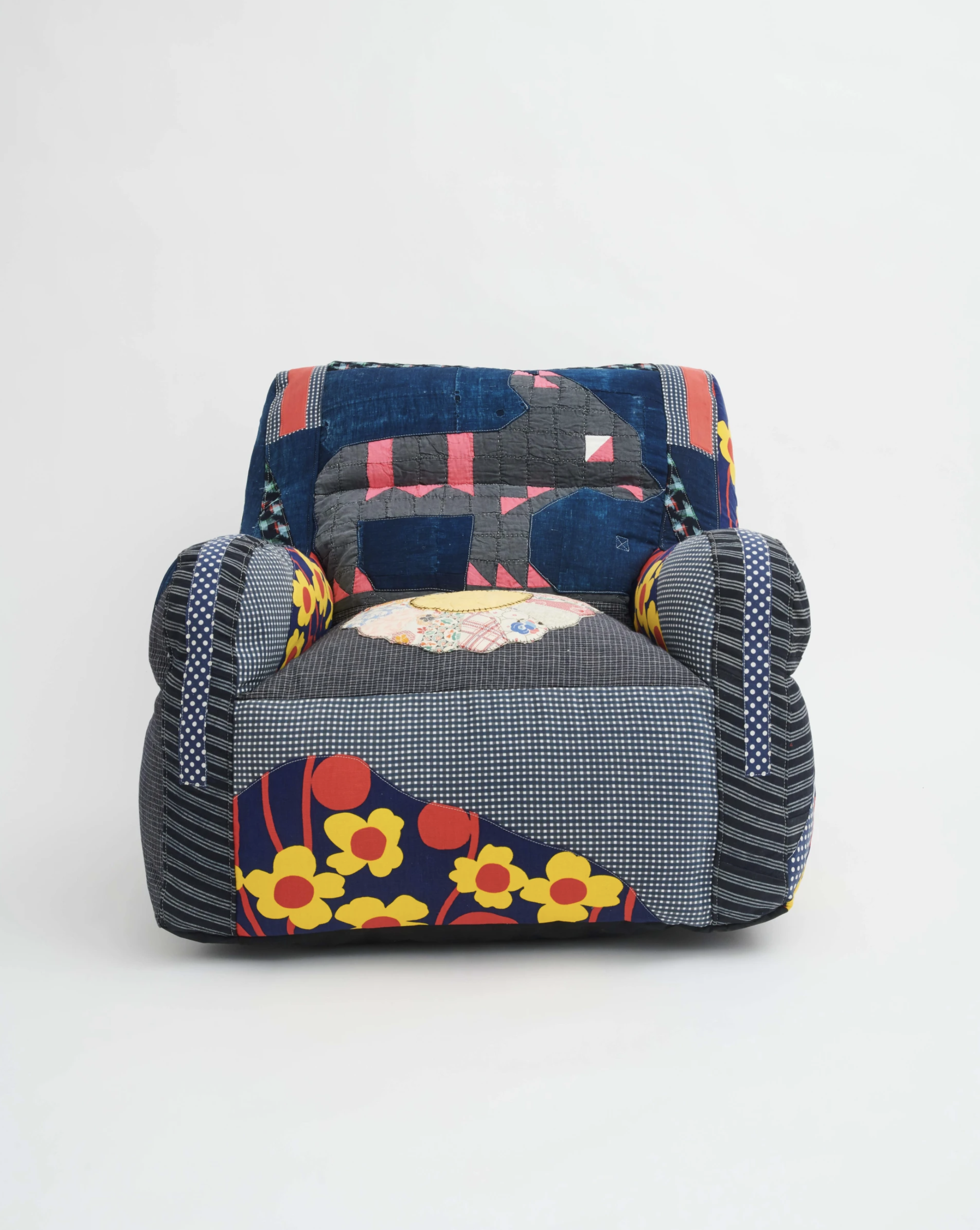 Patchwork armchair with colorful designs, including flowers and geometric patterns, against a white background.