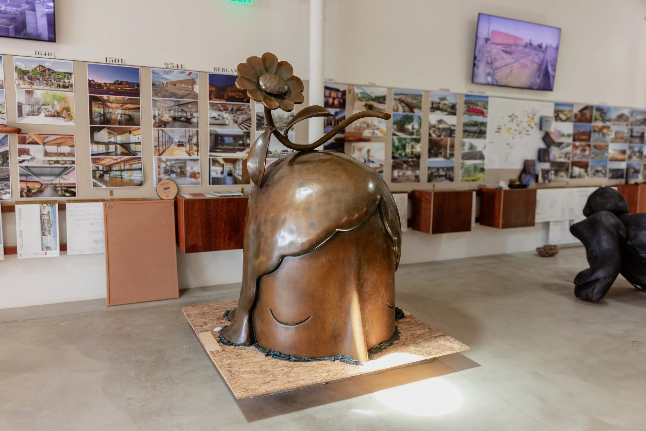 Bronze head sculpture with flower, art exhibit with photos on wall