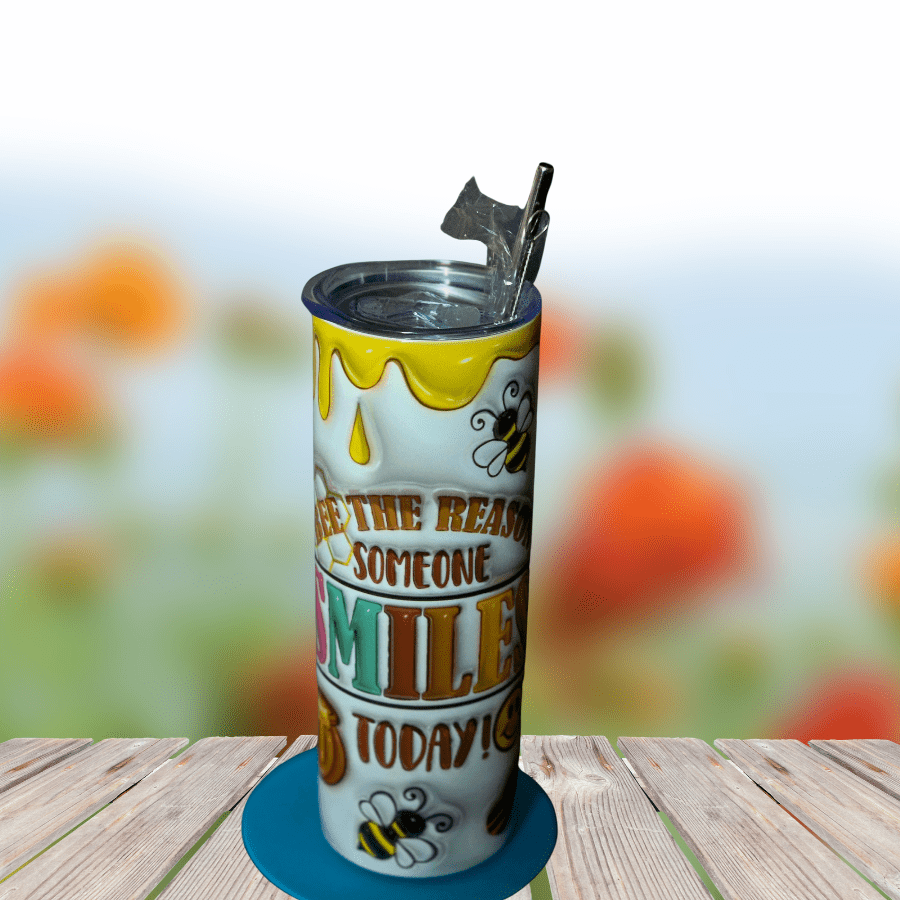 Decorative travel mug with honeycomb design and positive message, featuring bees and honey illustrations, placed on a wooden surface.
