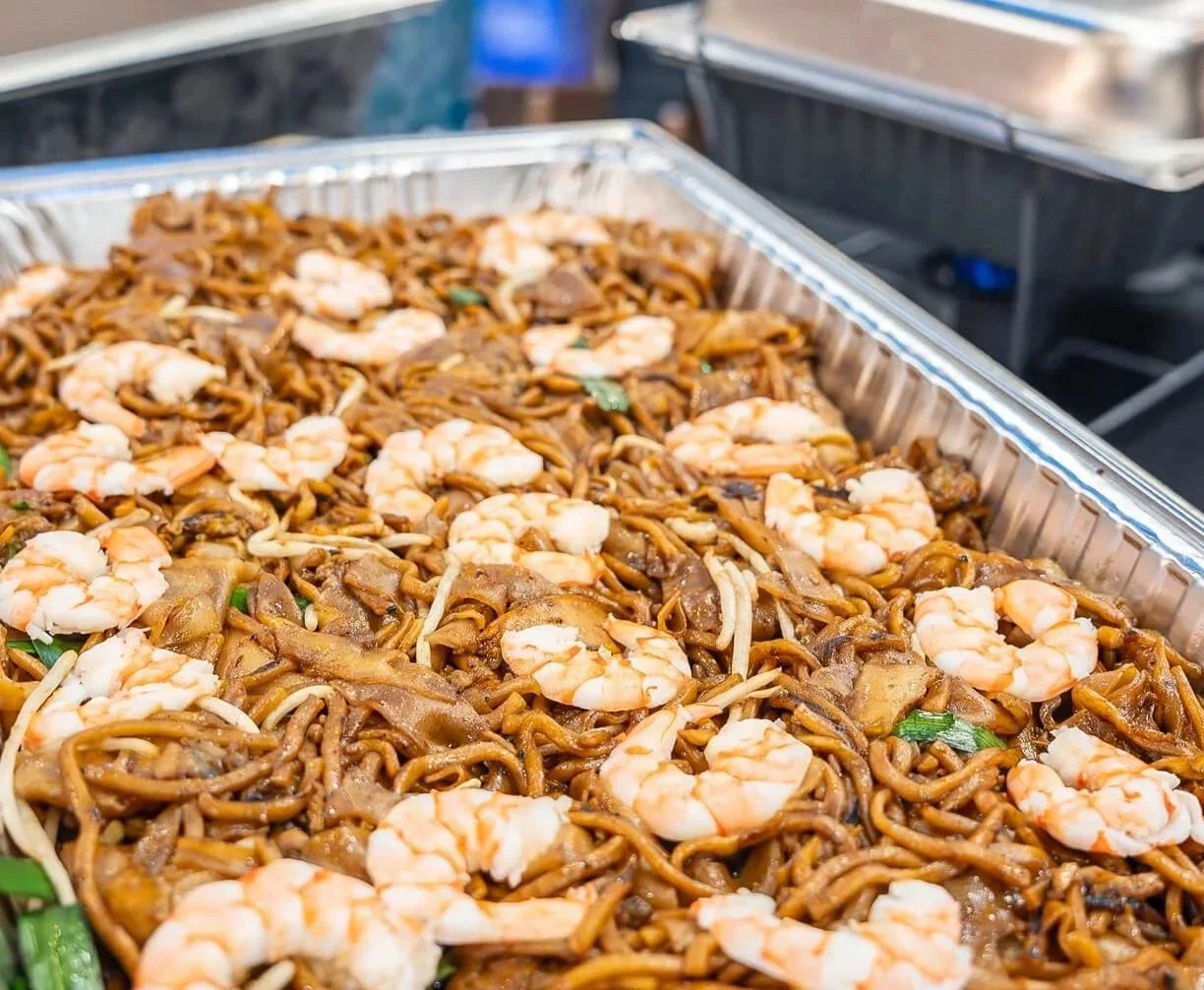 Tray of stir-fried noodles with shrimp and vegetables.