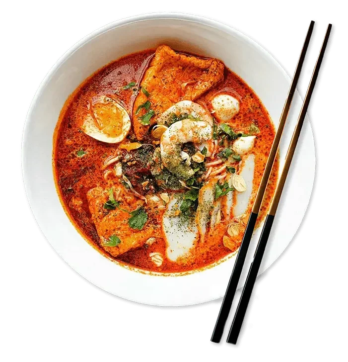 A bowl of spicy Asian seafood soup with shrimp, fish, tofu, boiled egg, and herbs, with chopsticks on the side.