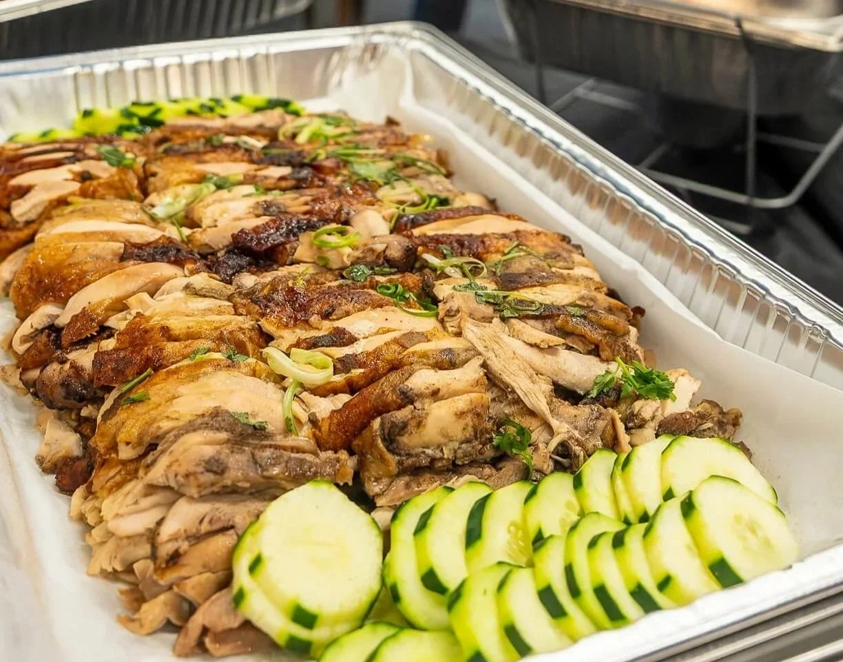 Tray of sliced roasted chicken garnished with green onions and herbs, accompanied by sliced zucchini.