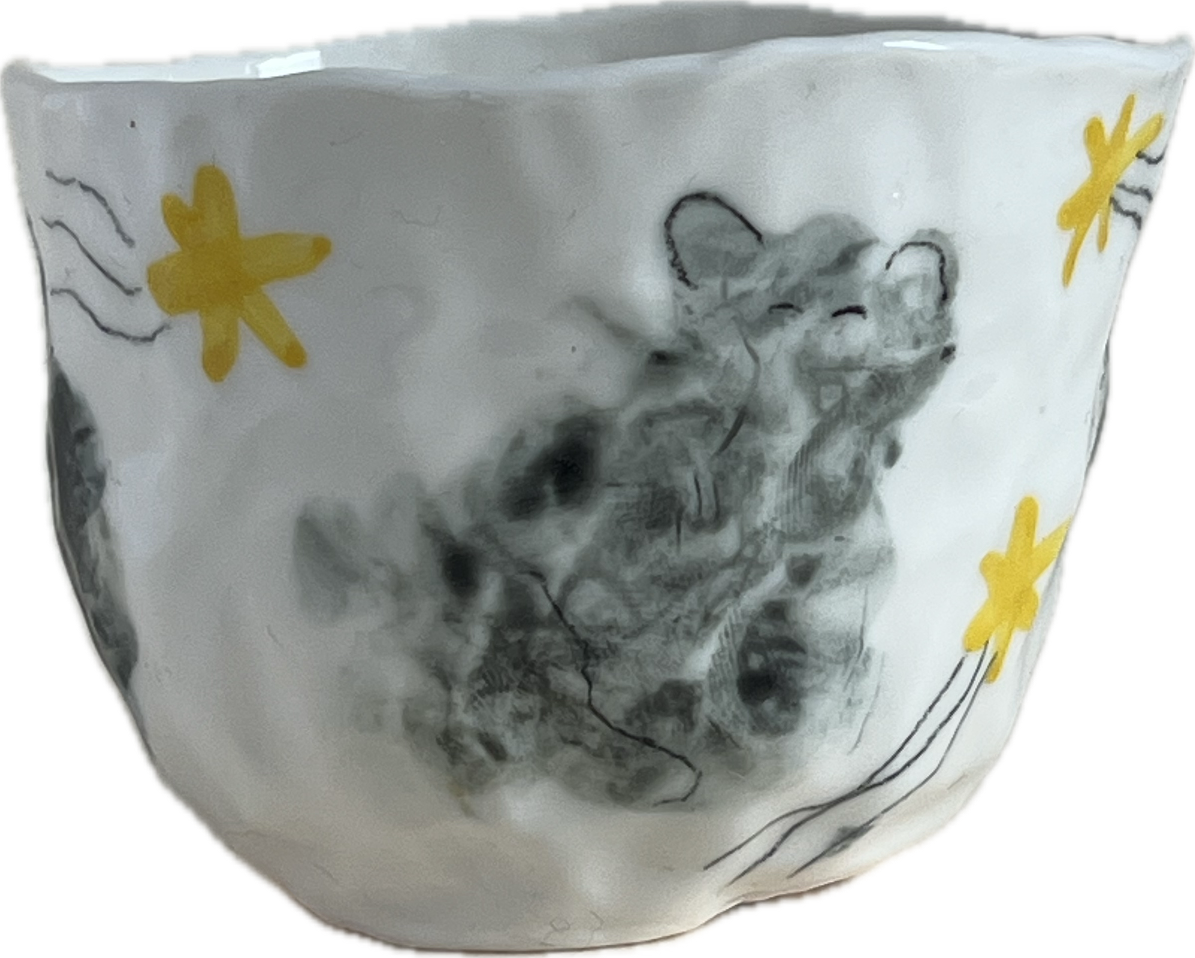 Une tasse en céramique blanche décorée d'un dessin noir représentant un animal, probablement une souris ou un rat. Elle est ornée de motifs de fleurs jaunes stylisées.
