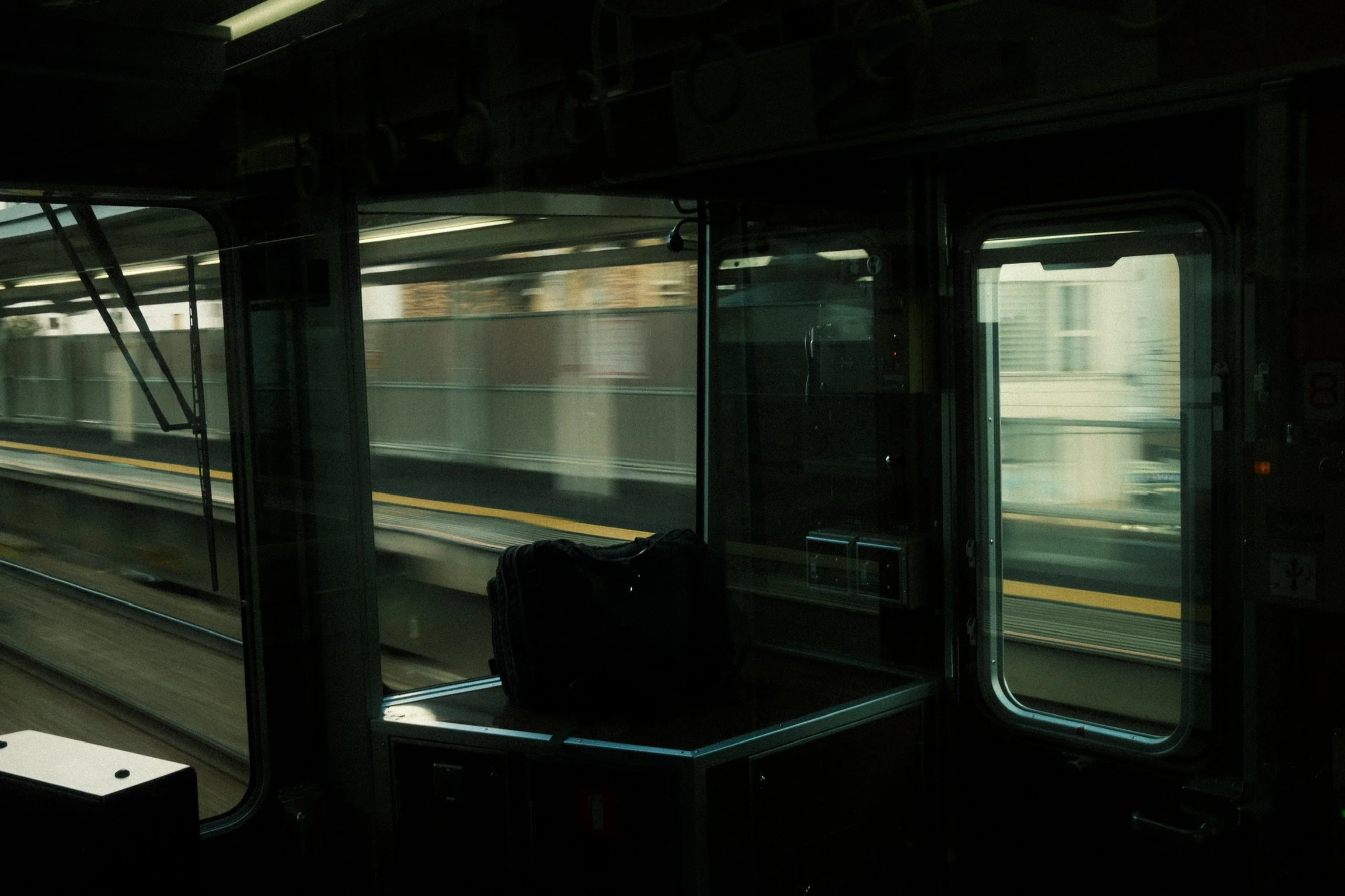 Inside view of an airport shuttle bus with large windows showing blurred scenery outside, dark interior with empty seats and luggage.