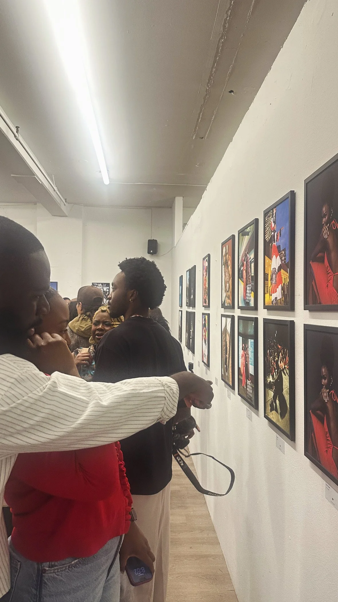 Visitors viewing photographs on a gallery wall at the Capturing Toronto photo exhibition.