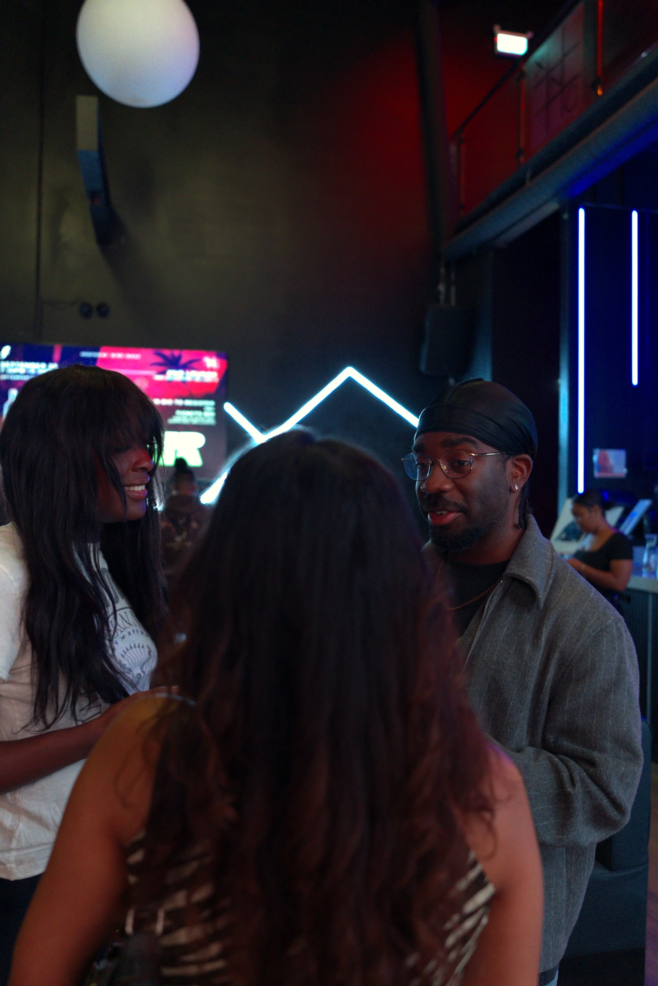 Guests chatting at a Toronto paint and sip night under neon lights.