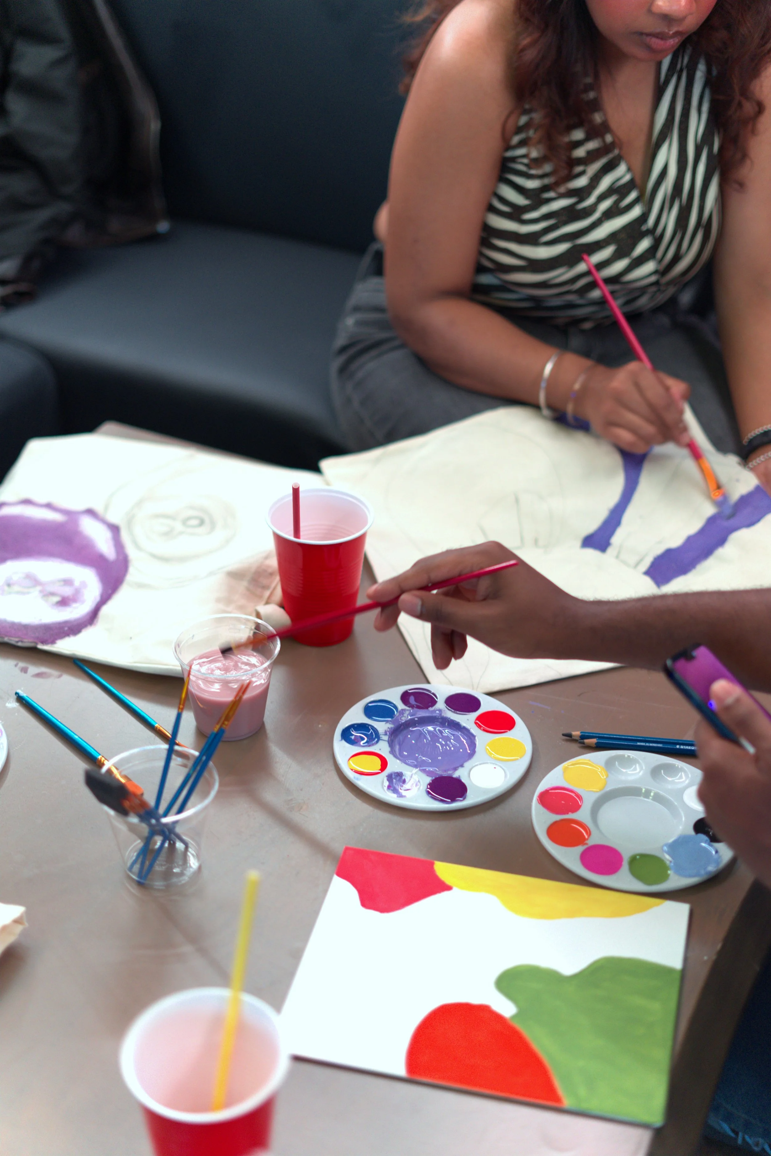 Guests painting at a table with paint, brushes and cups at a Toronto paint and sip night.
