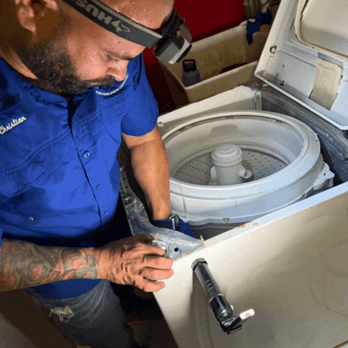 Hombre reparando una lavadora con una linterna en la cabeza