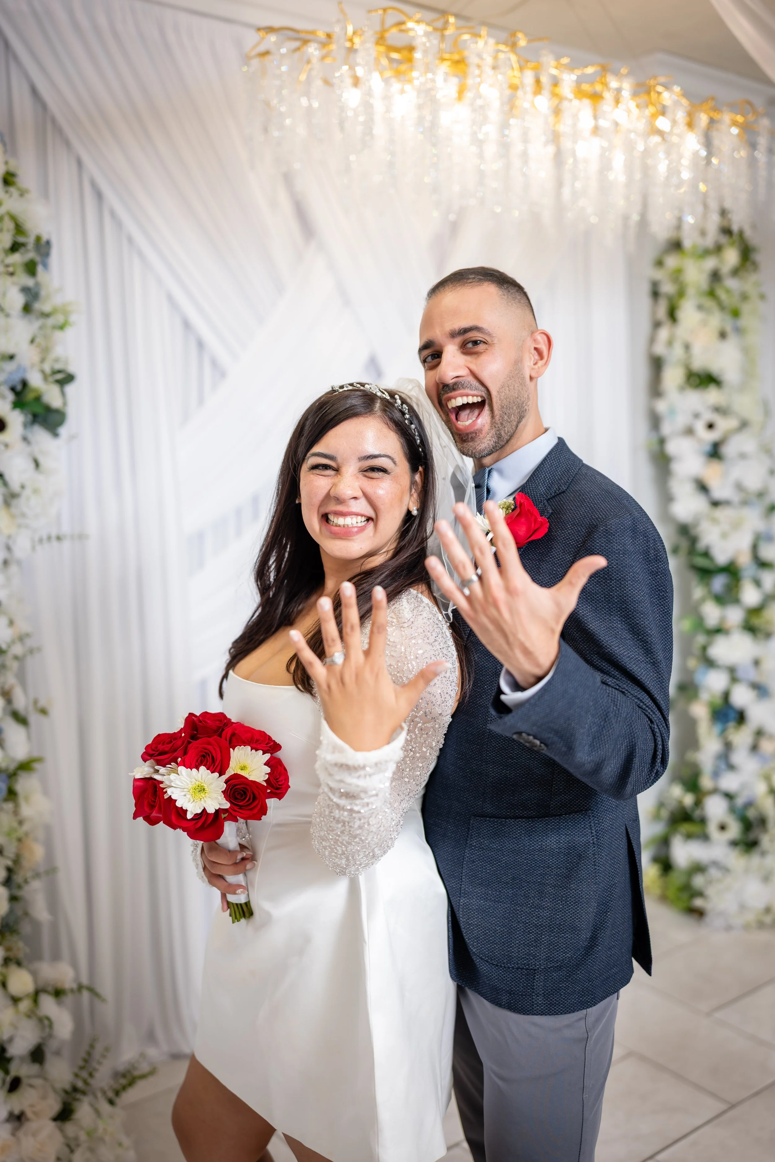 Happy bride and groom showing off their wedding rings at their wedding celebration.