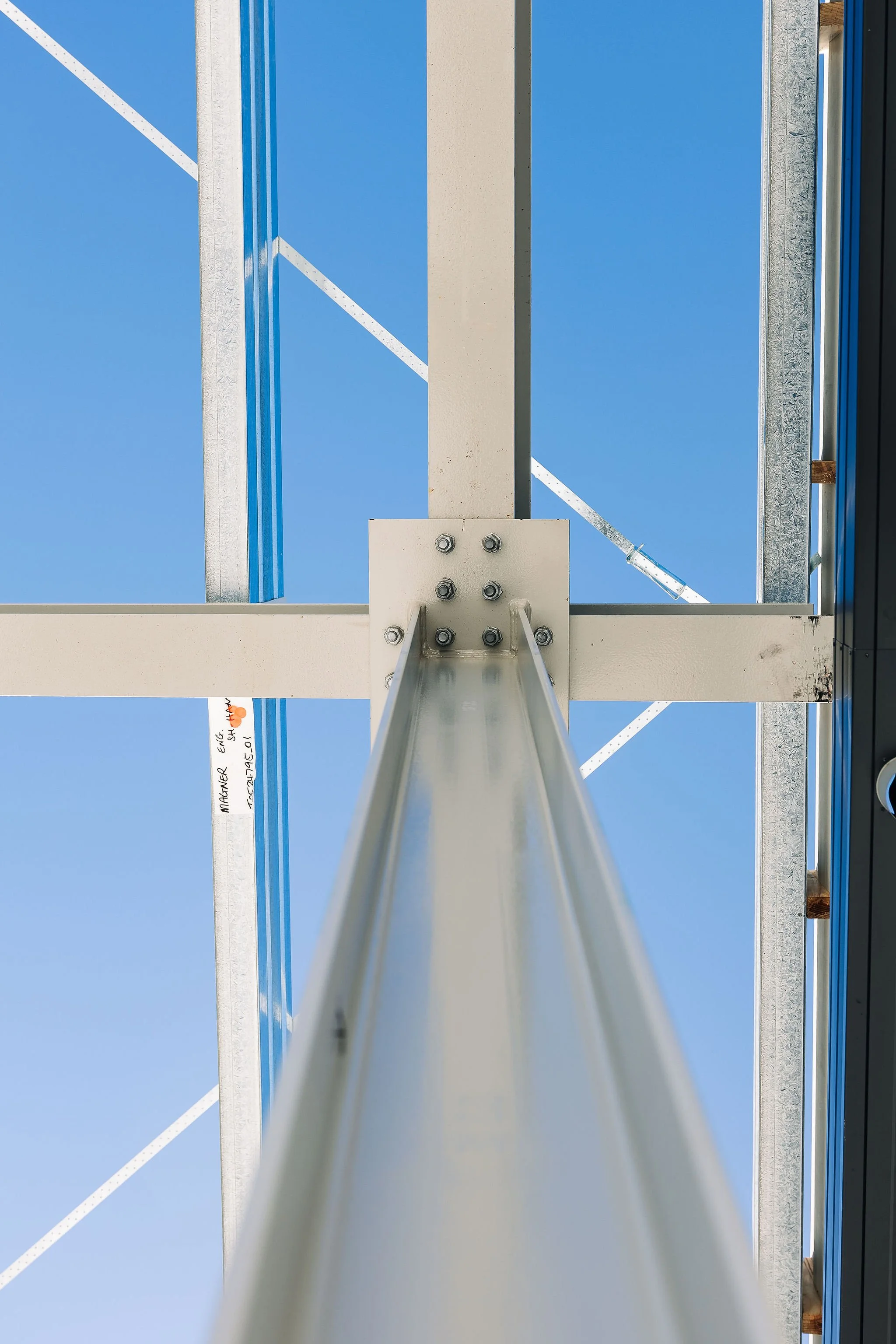 Looking up at a metal ladder and support beams against a clear blue sky.