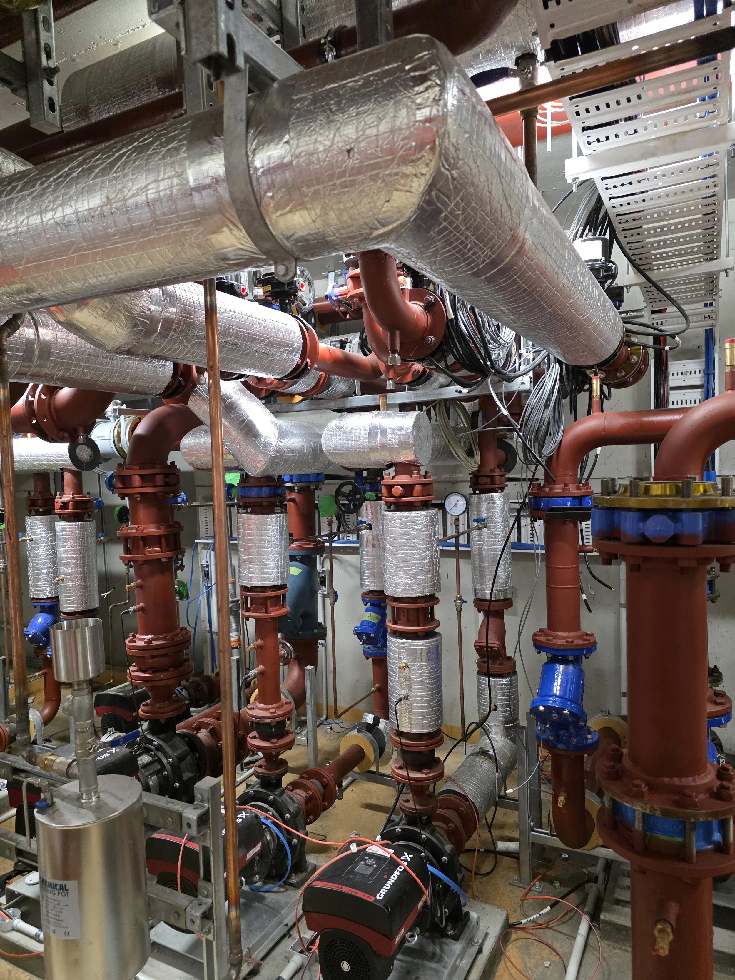 A complex network of pipes, valves, and machinery in an industrial setting, possibly part of a plumbing or HVAC system.