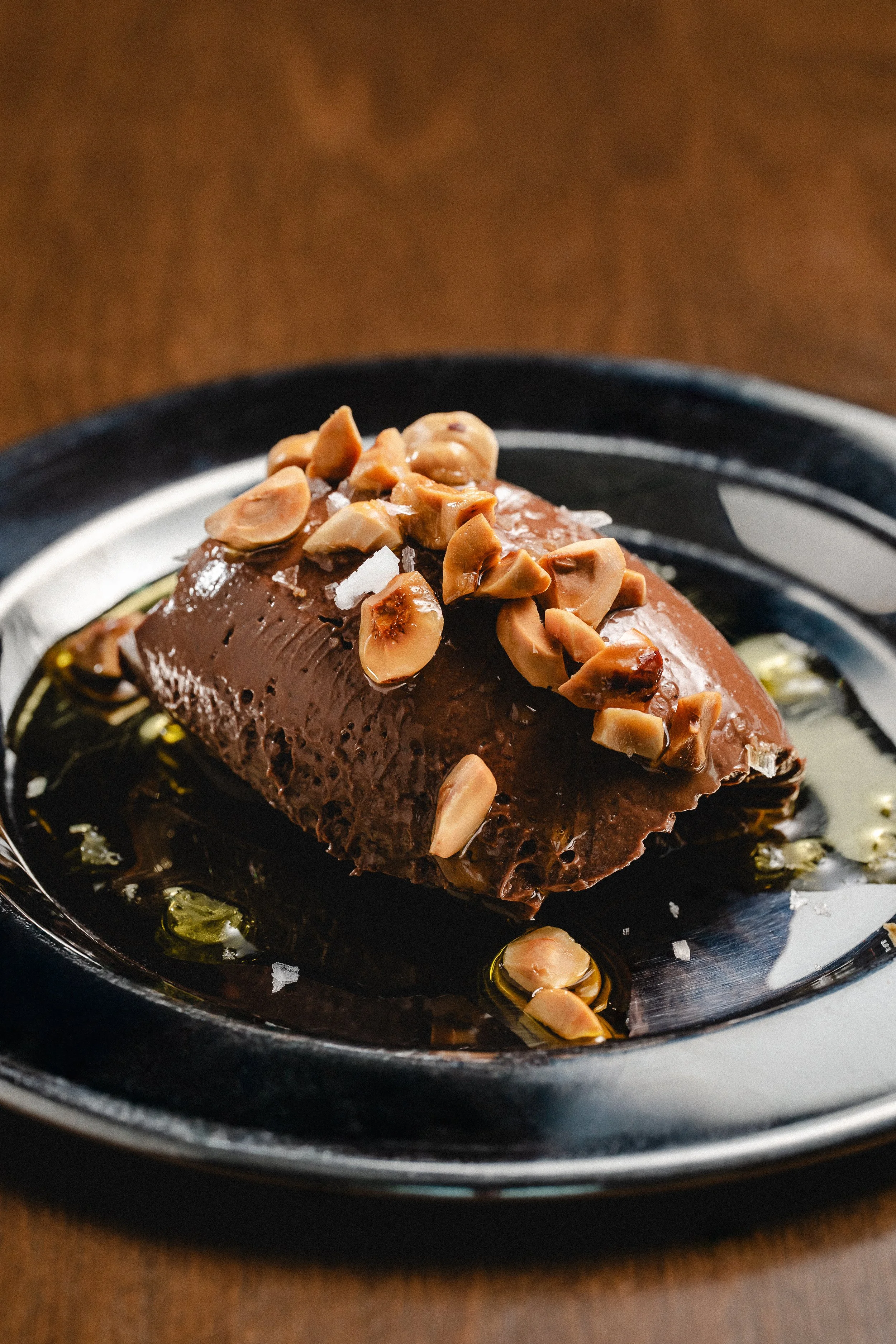 Postre de chocolate con nueces en un plato negro.