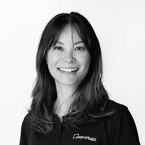 Black and white portrait of a woman with shoulder-length hair, wearing a collared shirt with a logo on it, smiling at the camera.