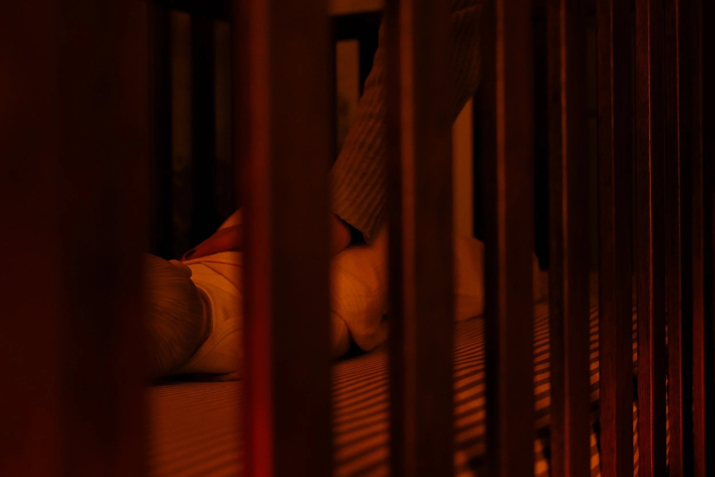 Lauren Harvey, Atlanta newborn care specialist, soothing a baby in a crib during overnight newborn care support.