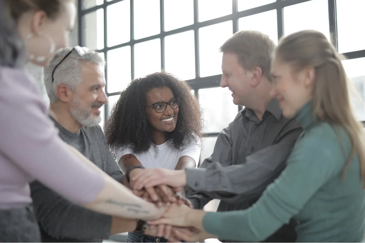 Agile team in a group hug, smiling and celebrating unity and collaboration in a modern, flexible workspace.