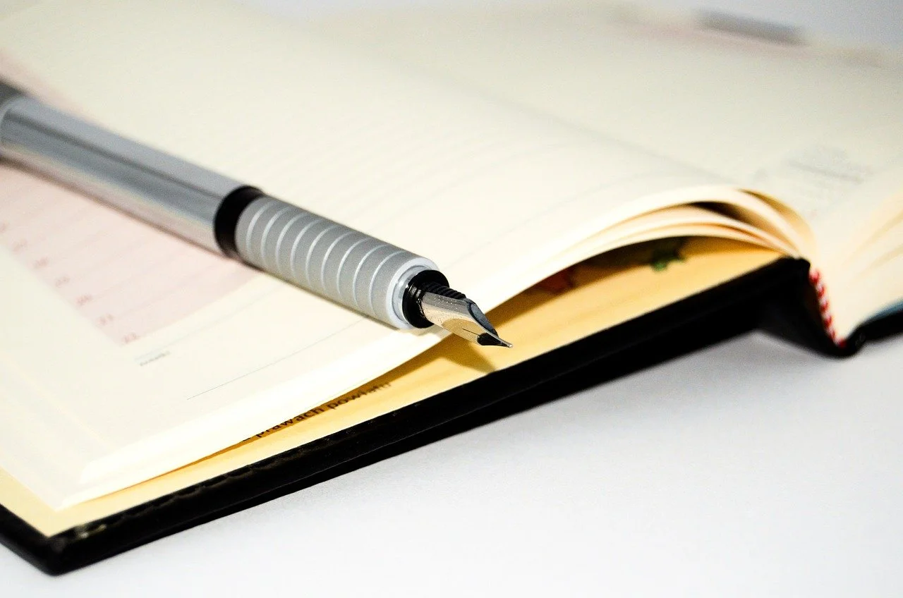 Desk planner opened with a silver fountain pen, representing business scheduling.