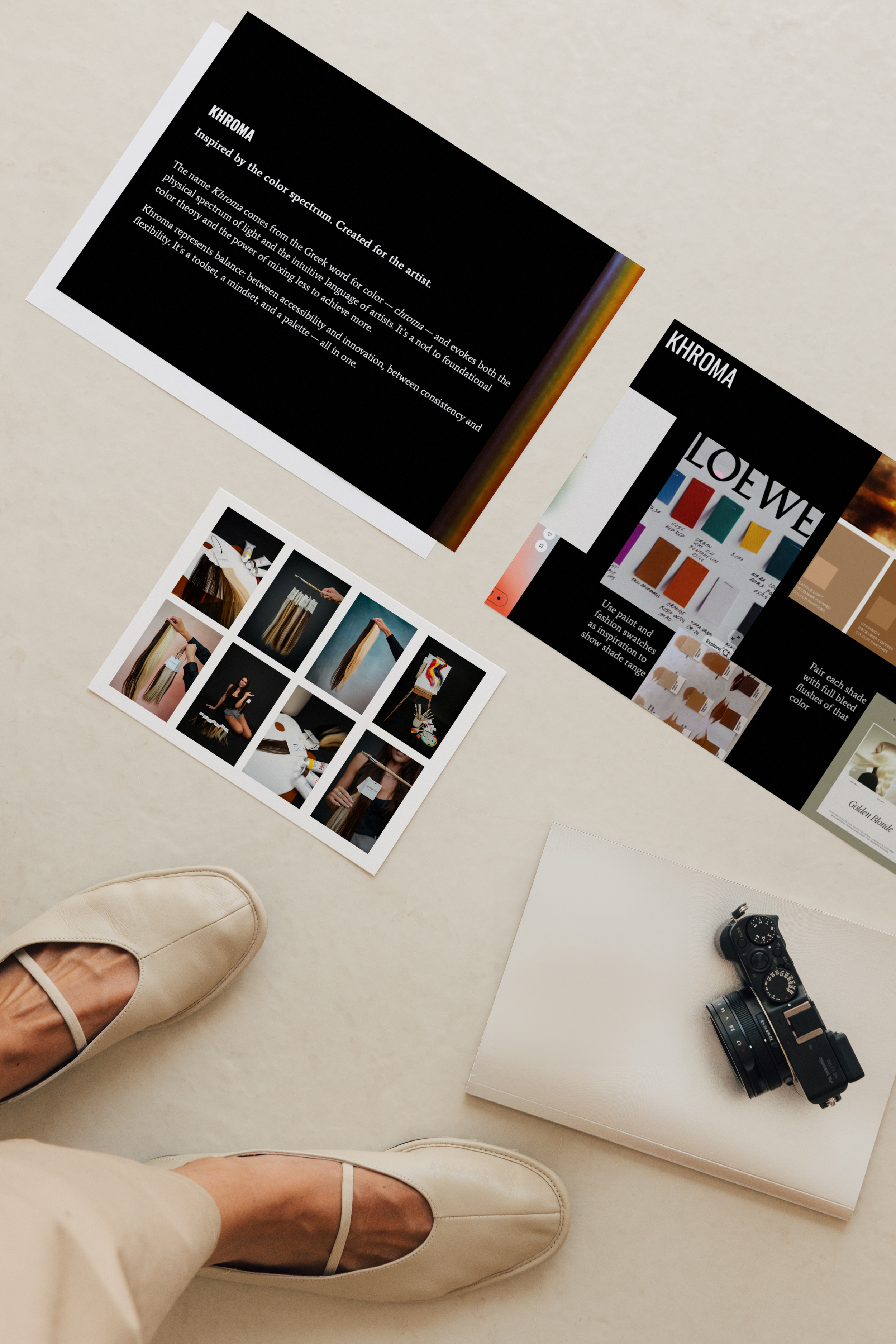 A person's feet in beige shoes standing on a white surface surrounded by various magazines, photographs, a camera, and a white notebook.
