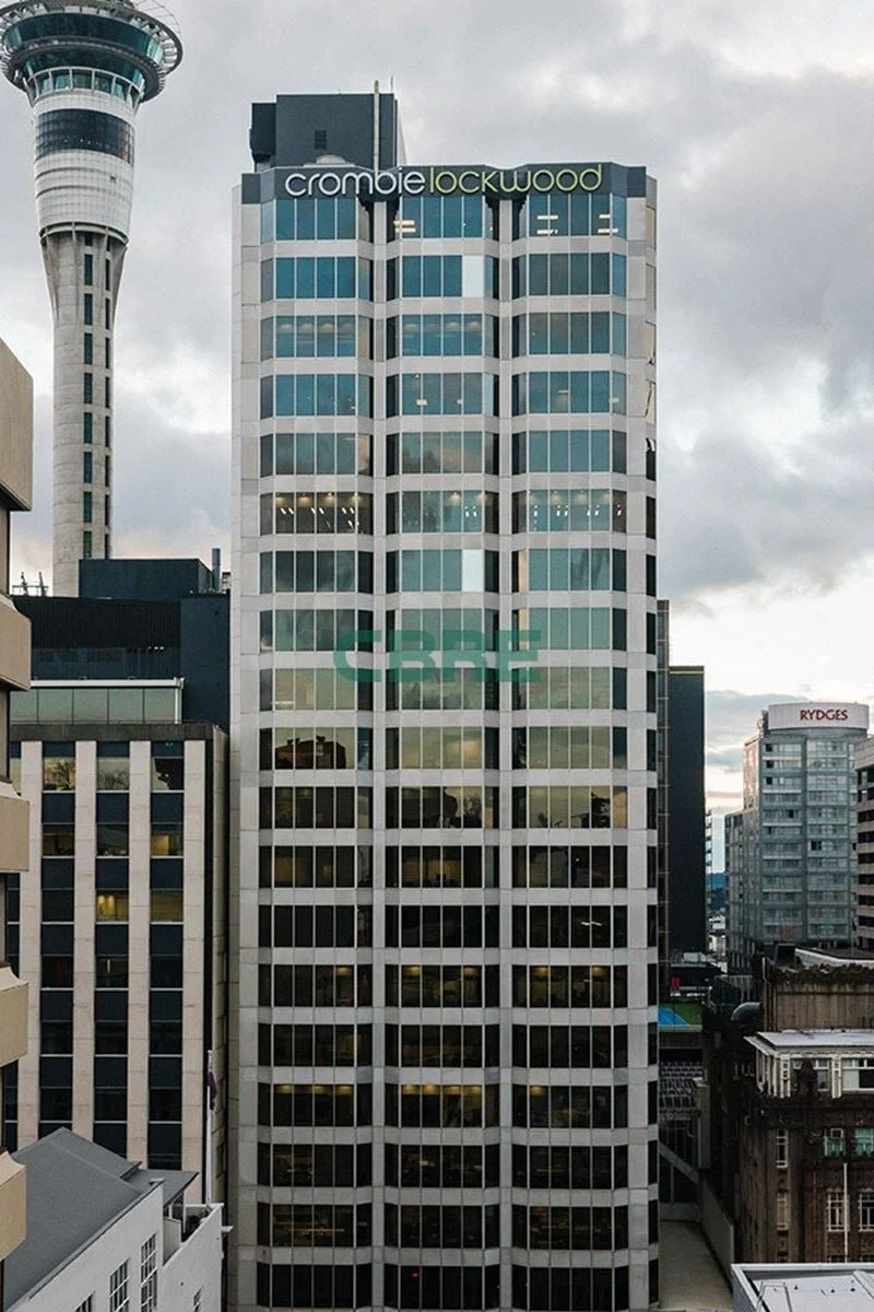 A city skyline featuring a tall office building with glass windows and the name "Crombie Lockwood" at the top. Part of the Space Needle is visible on the left, and other high-rise buildings are in the background.
