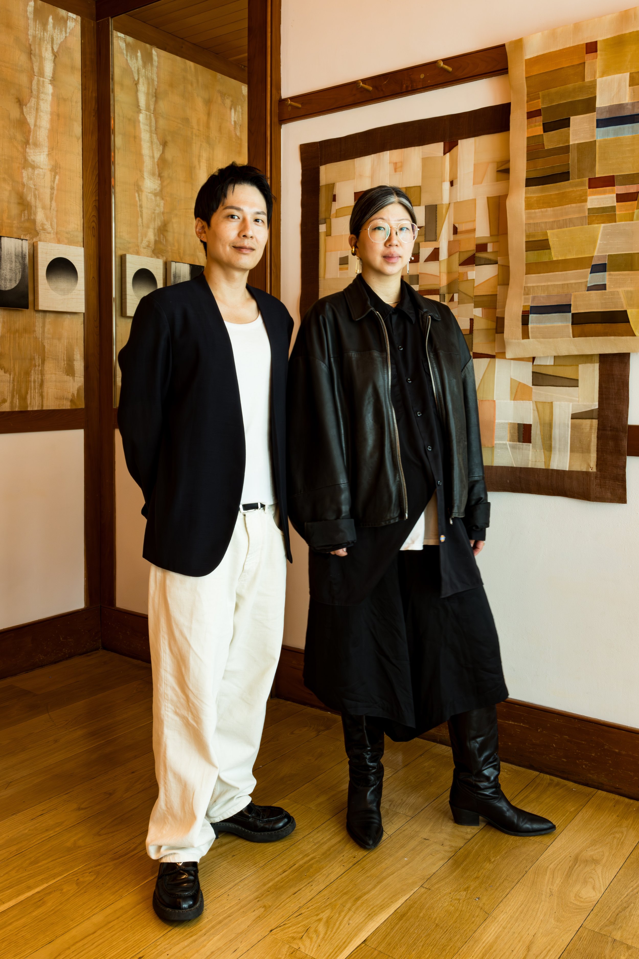 Two women standing inside an art gallery in front of abstract artwork on the wall.