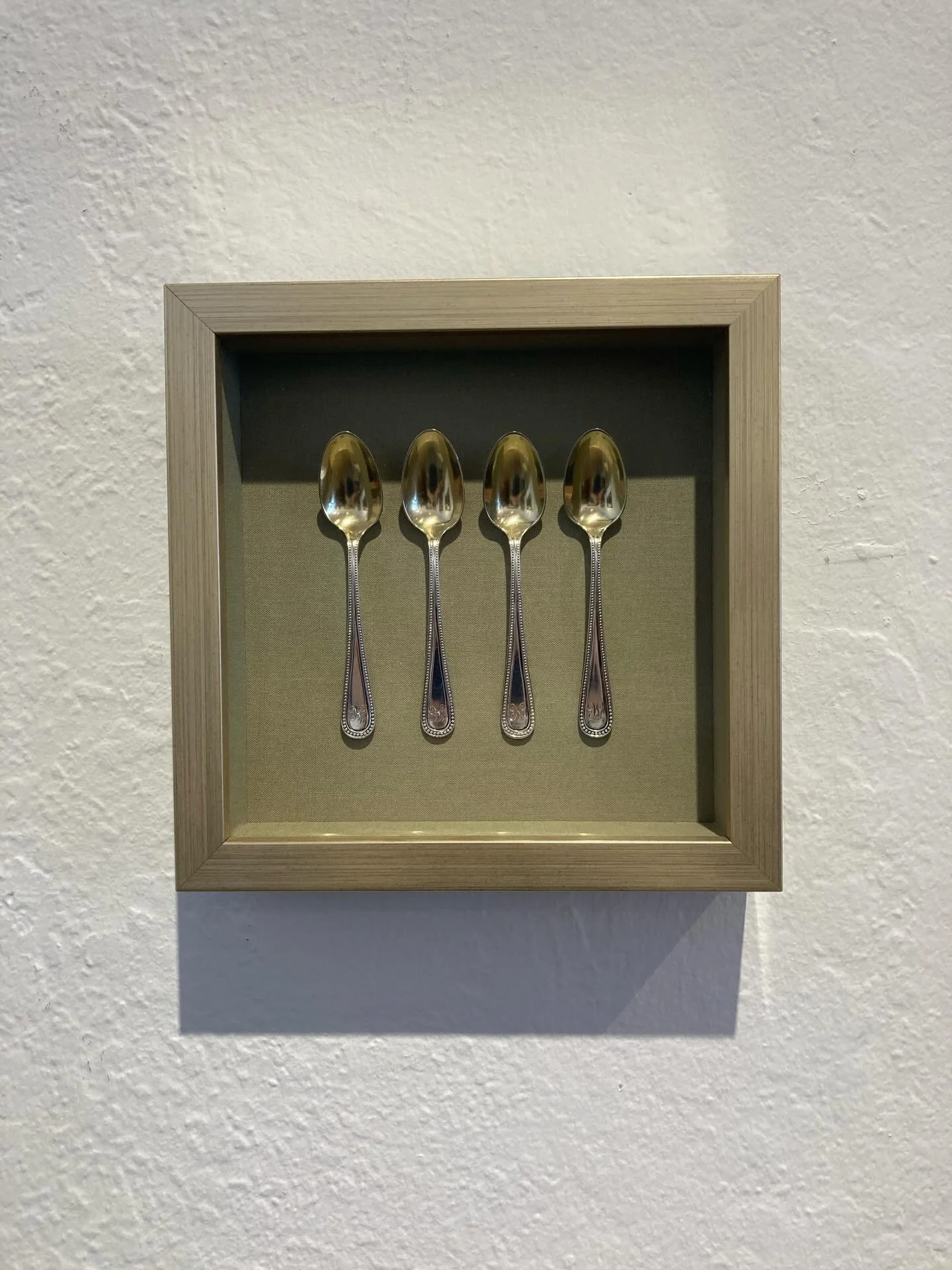 Charming little shadow boxes displaying cherished items can add intimate and special points of interest on your walls!  These spoons are floating on a fabric mat that adds subtle texture and richness and then framed with a soft gold Studio moulding.
