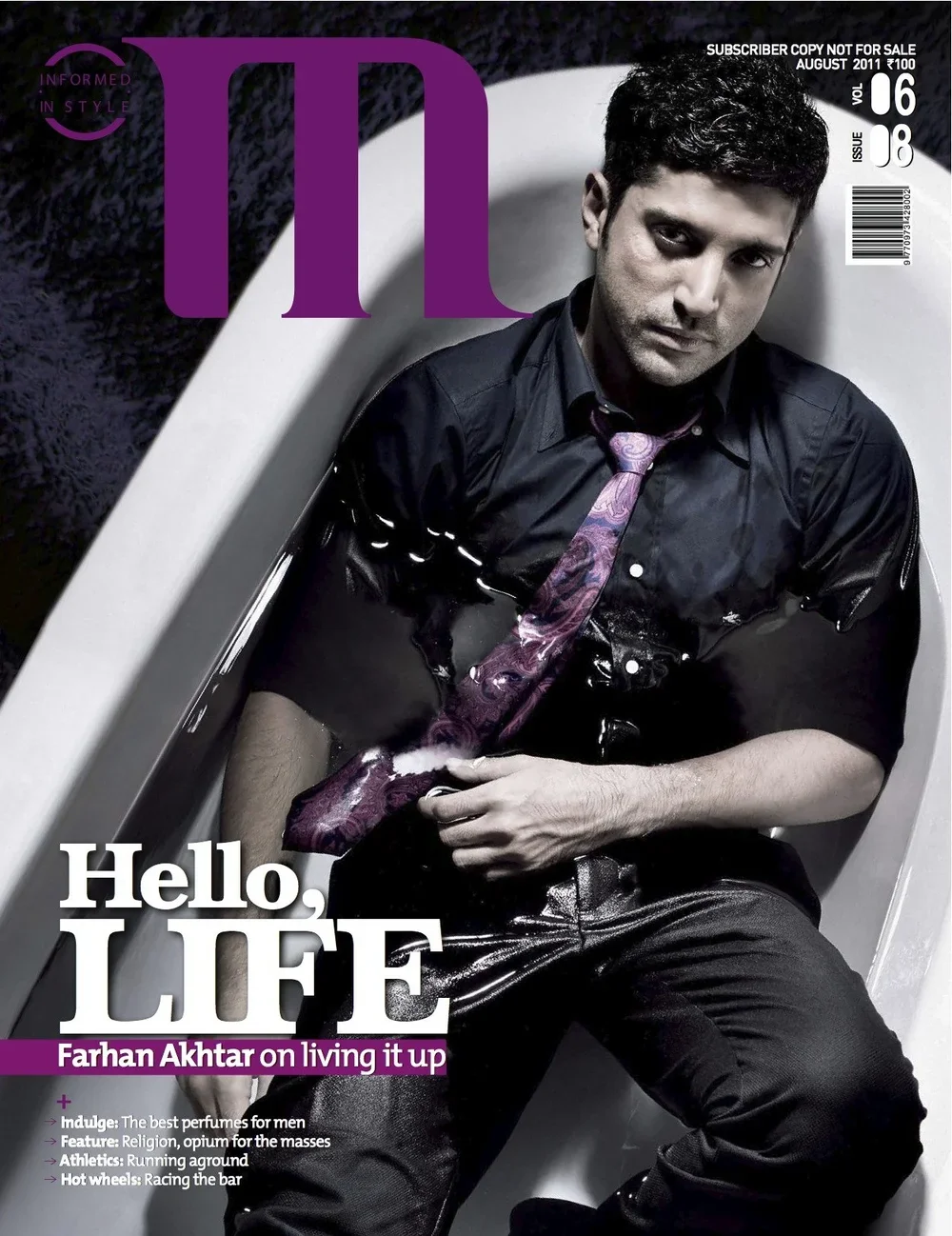 Cover of a magazine featuring a man sitting in a white bathtub, wearing a black shirt and a colorful pink and purple tie, with a serious expression.