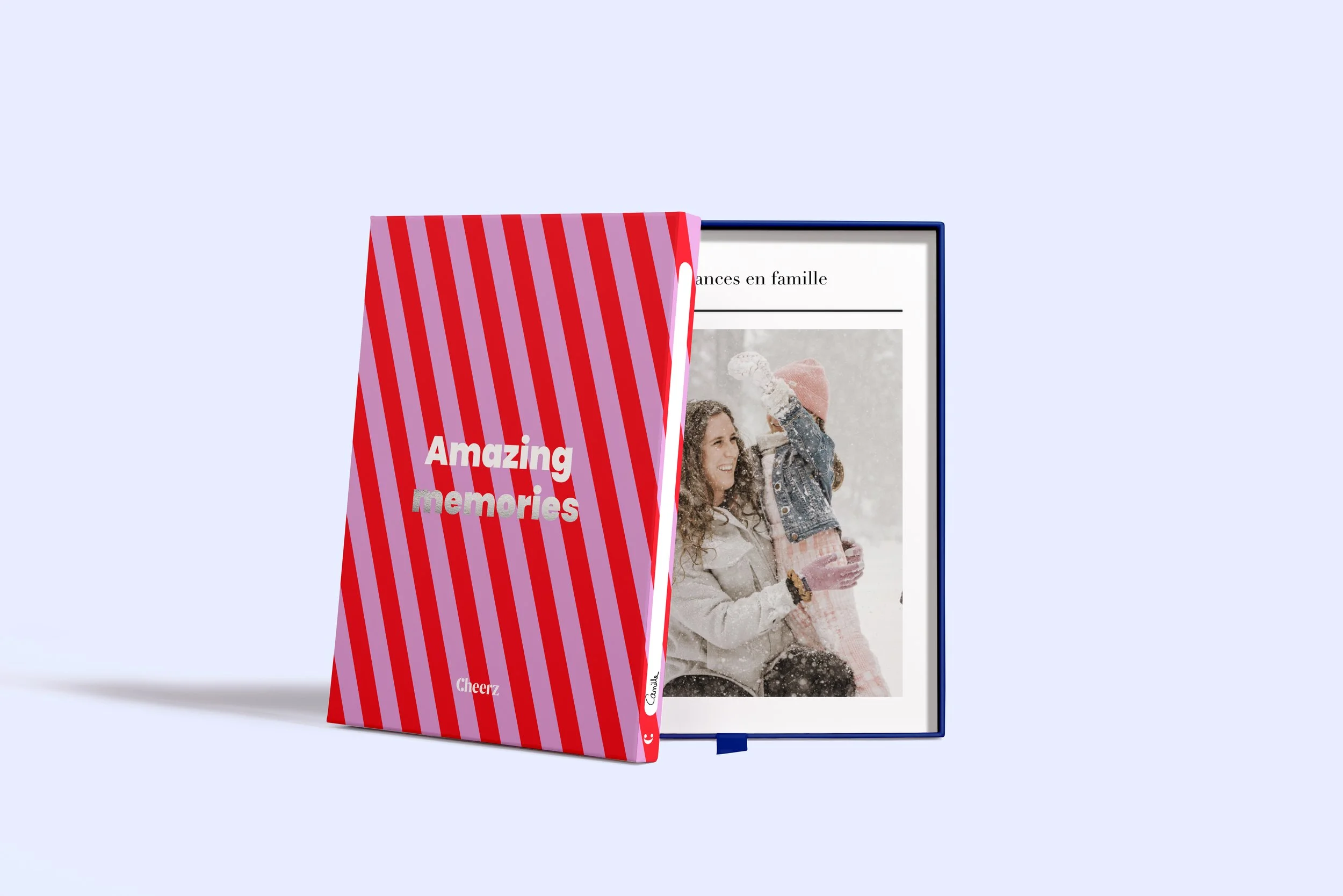 Un livre de souvenirs avec une couverture à rayures rouges et roses, intitulé "Amazing memories", à côté d'un cadre photo avec une image d'une mère et sa fille en hiver.