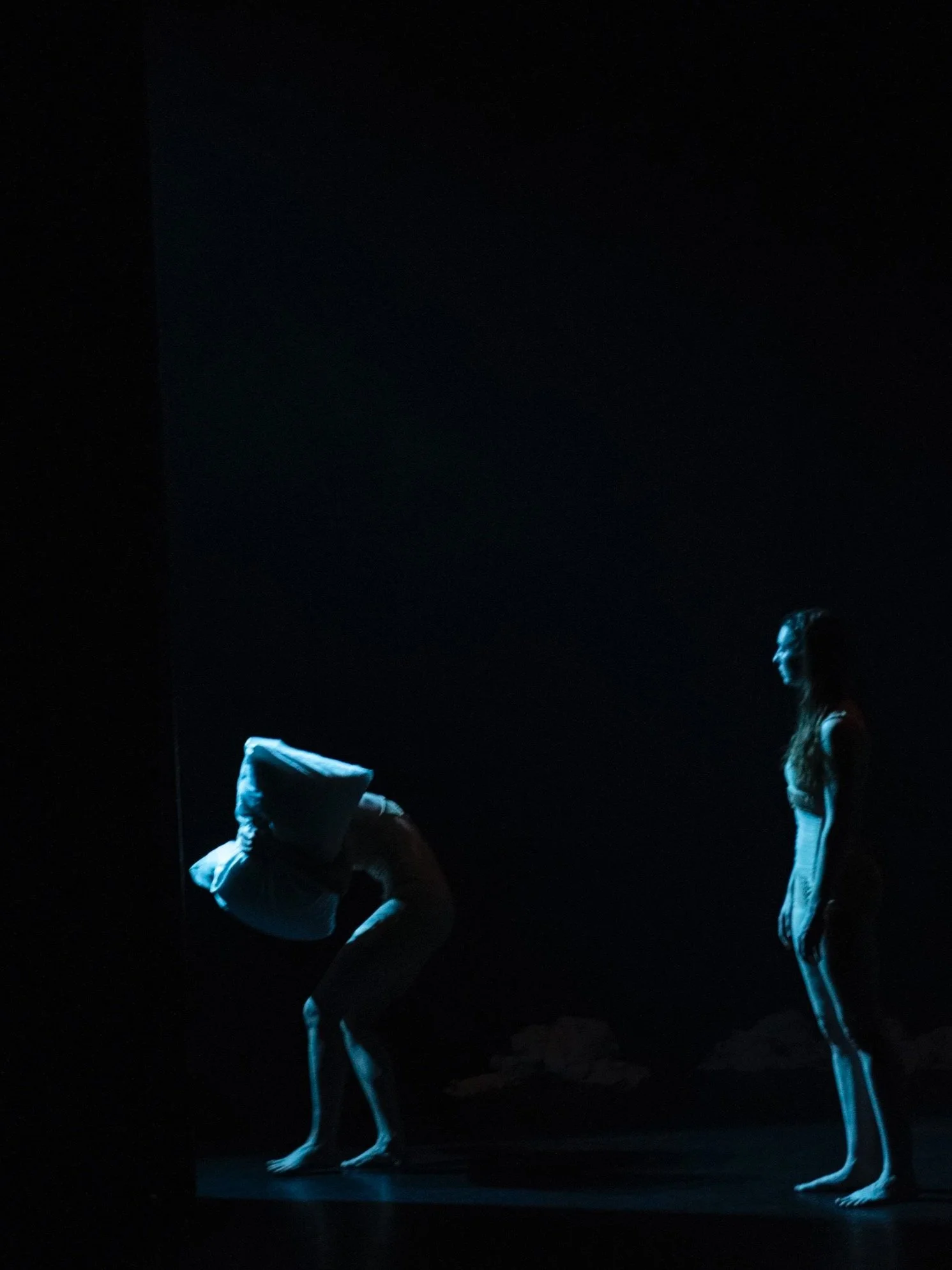 Two dancers in a blue light.