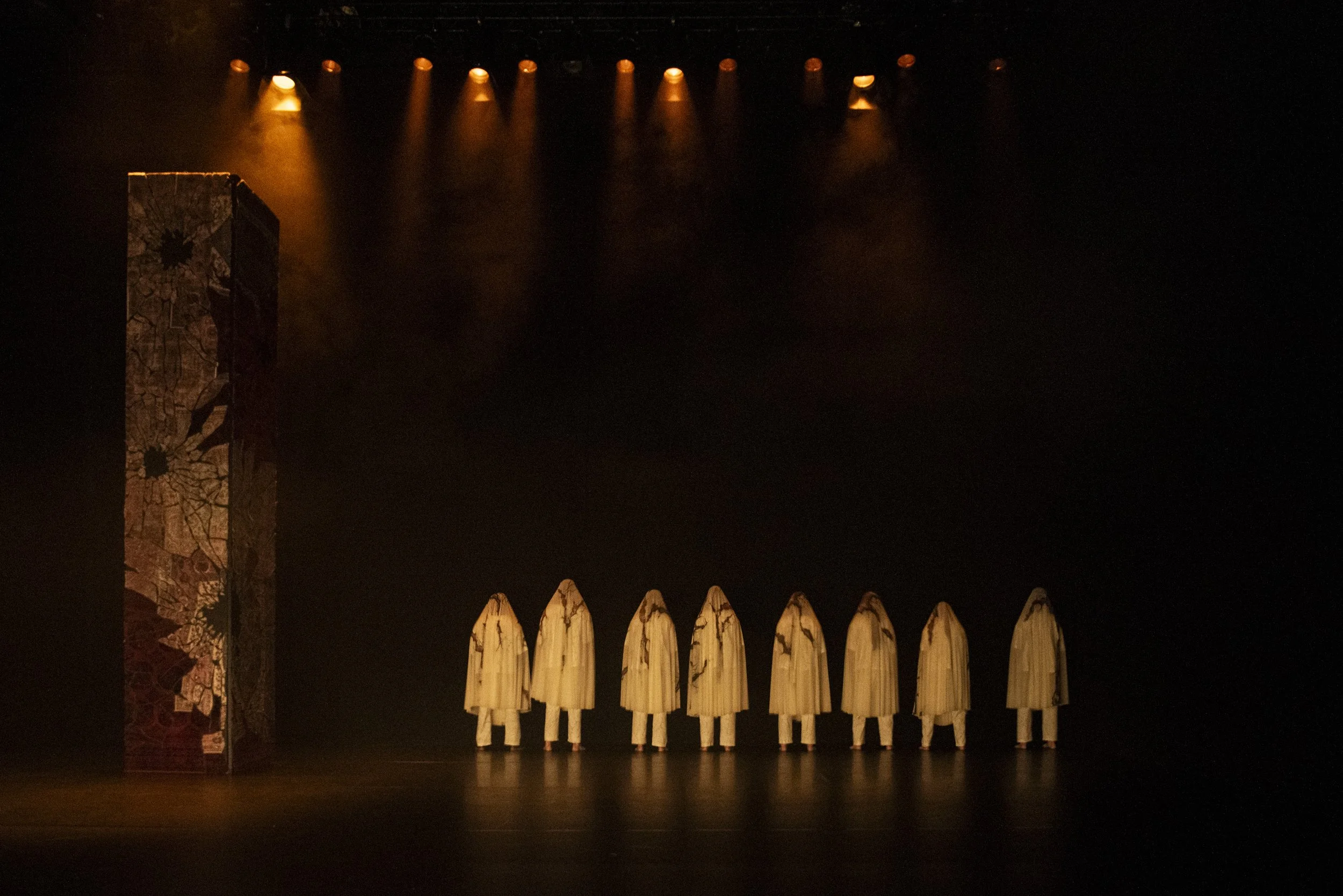 Performers in the distance wearing white shrouds.