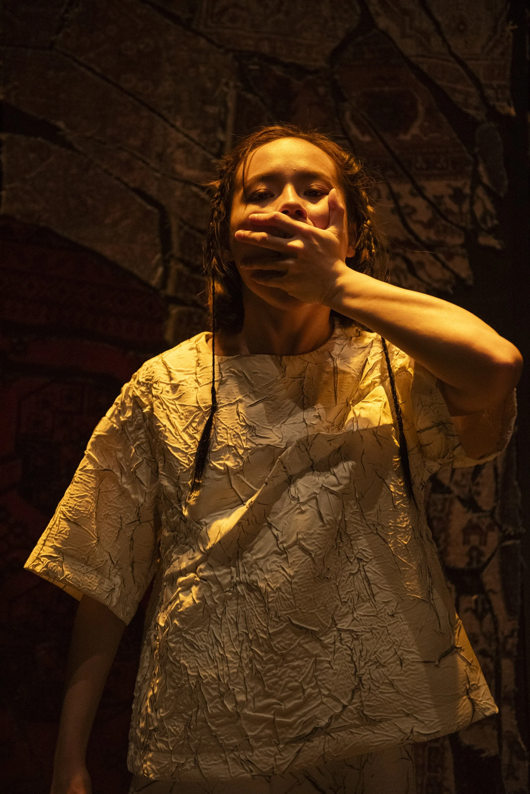Dancer wearing white cracked fabric and covering her mouth.