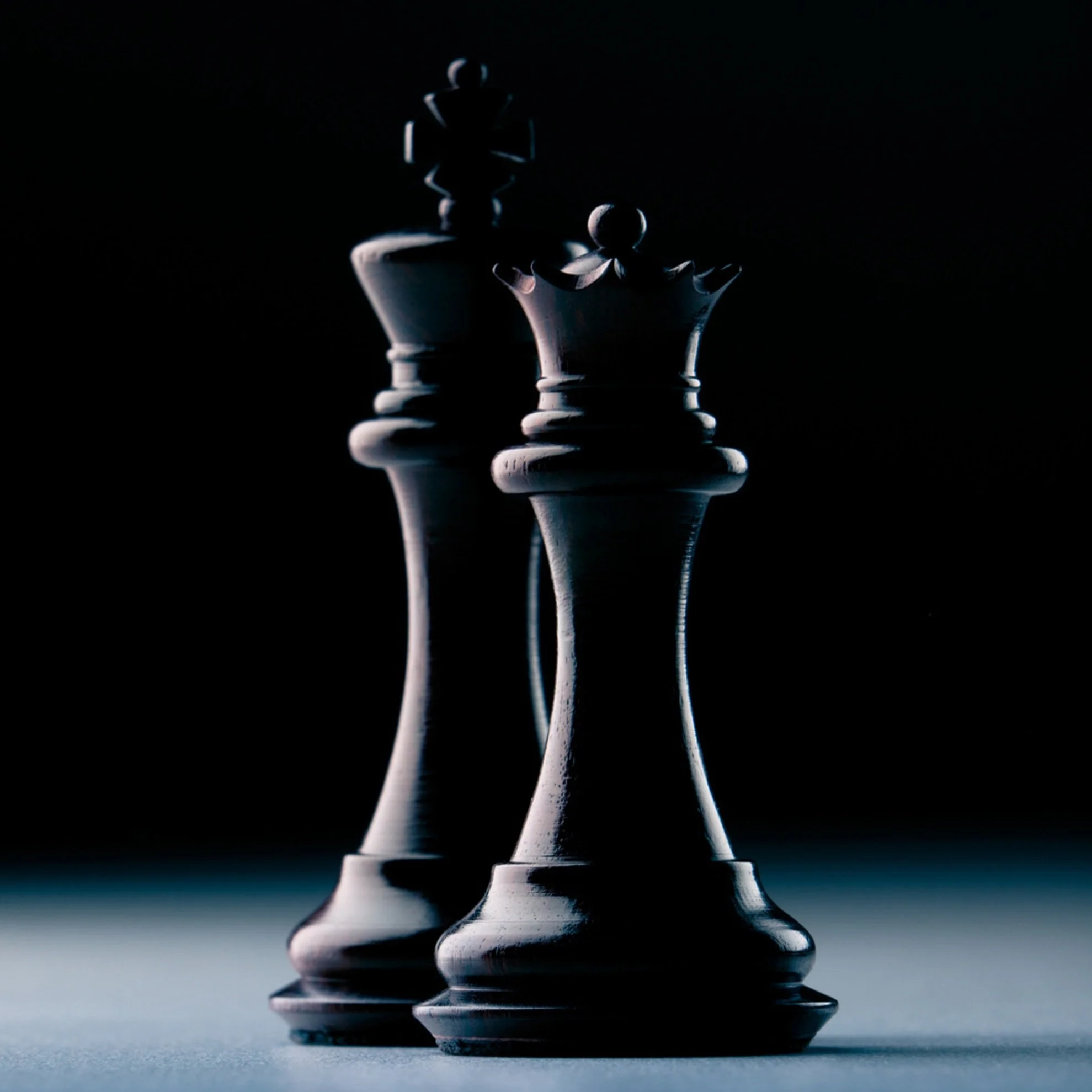 Close-up of a dark chess king and queen against a black background