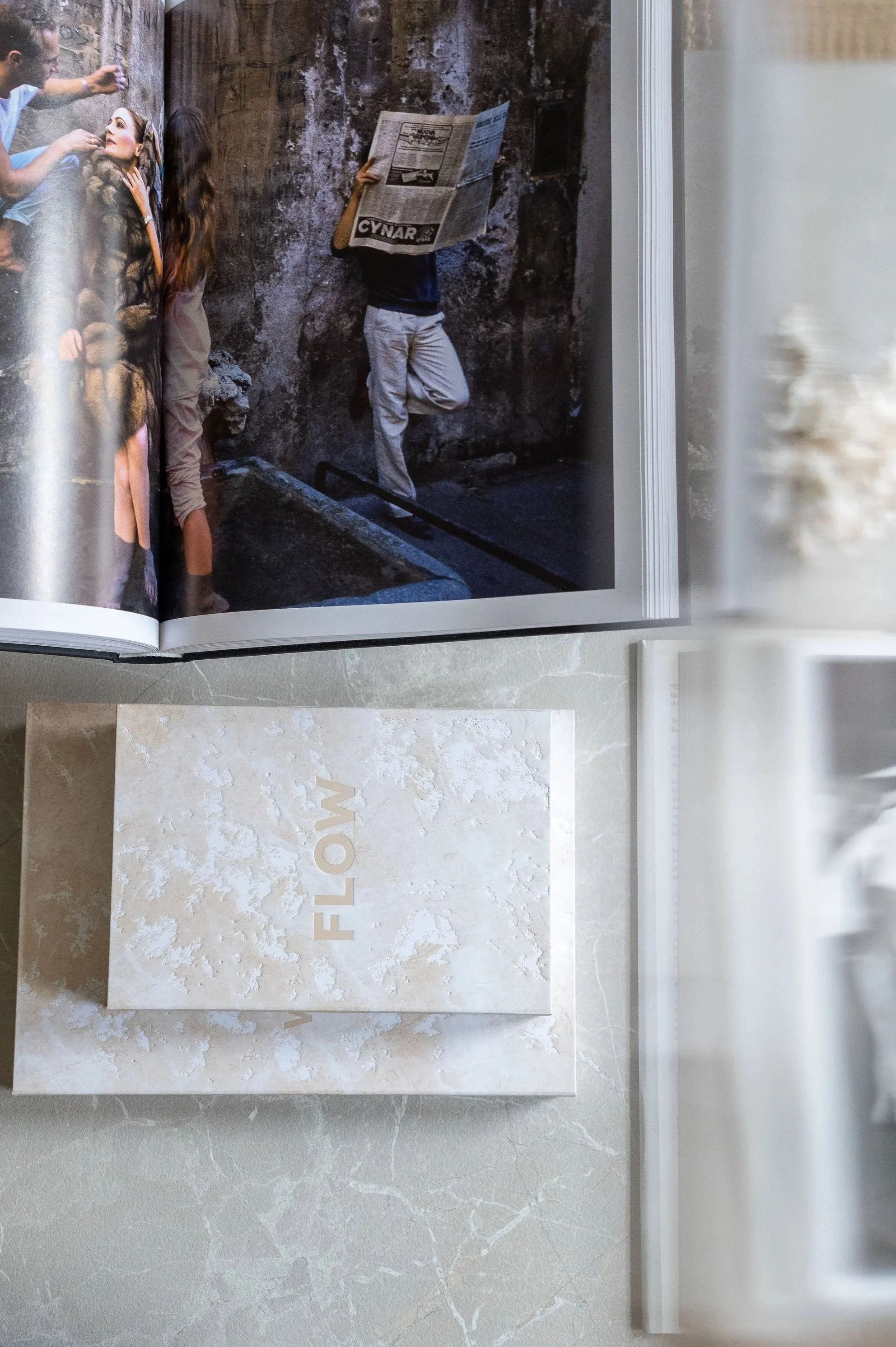 Open magazine showing a photo of people in an alley, with one person reading a newspaper, next to a box with the word 'FLOOR' on it.